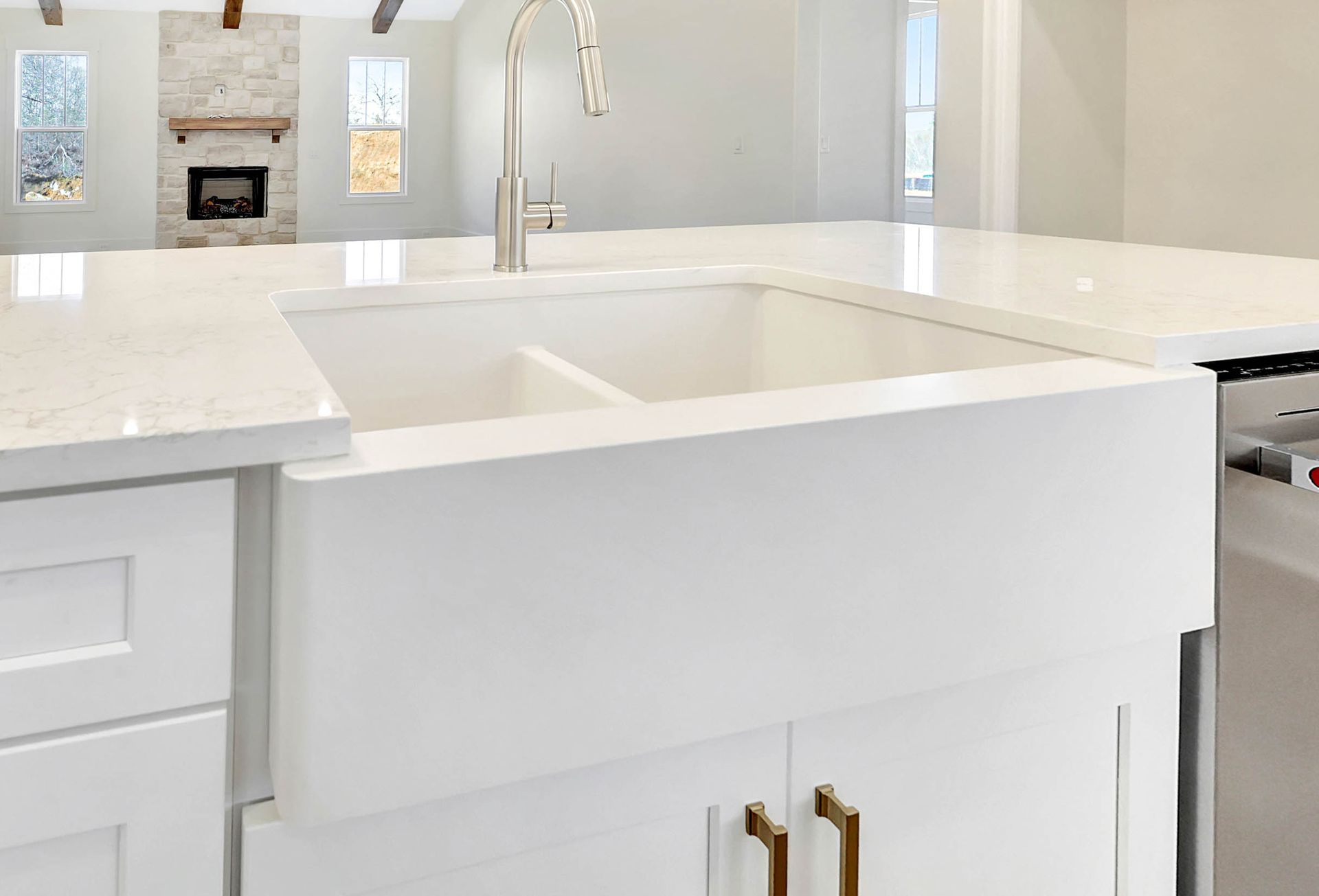 A kitchen with a large white sink and white cabinets.