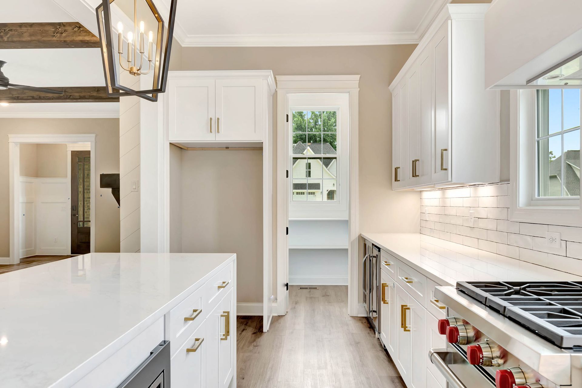 A kitchen with white cabinets , a stove , and a window.