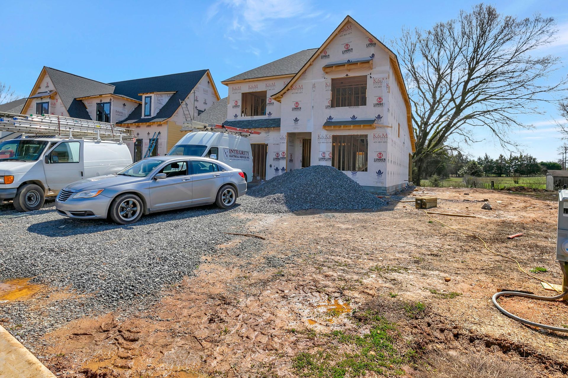 A car is parked in front of a house under construction.