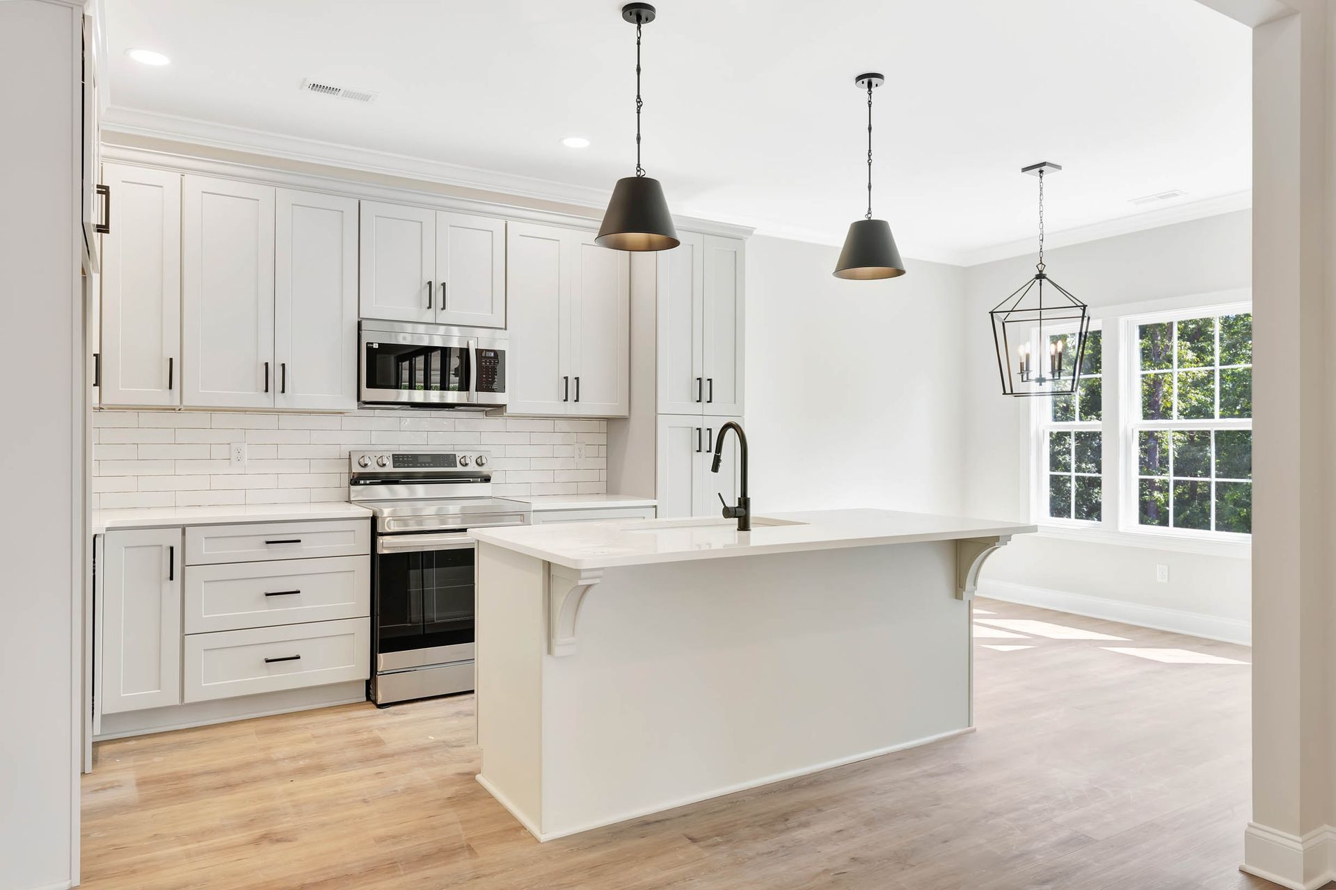 A kitchen with white cabinets , stainless steel appliances , and a large island.