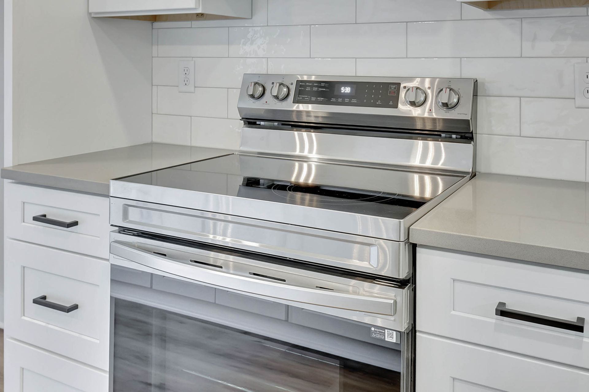 A kitchen with a stainless steel stove top oven and white cabinets.