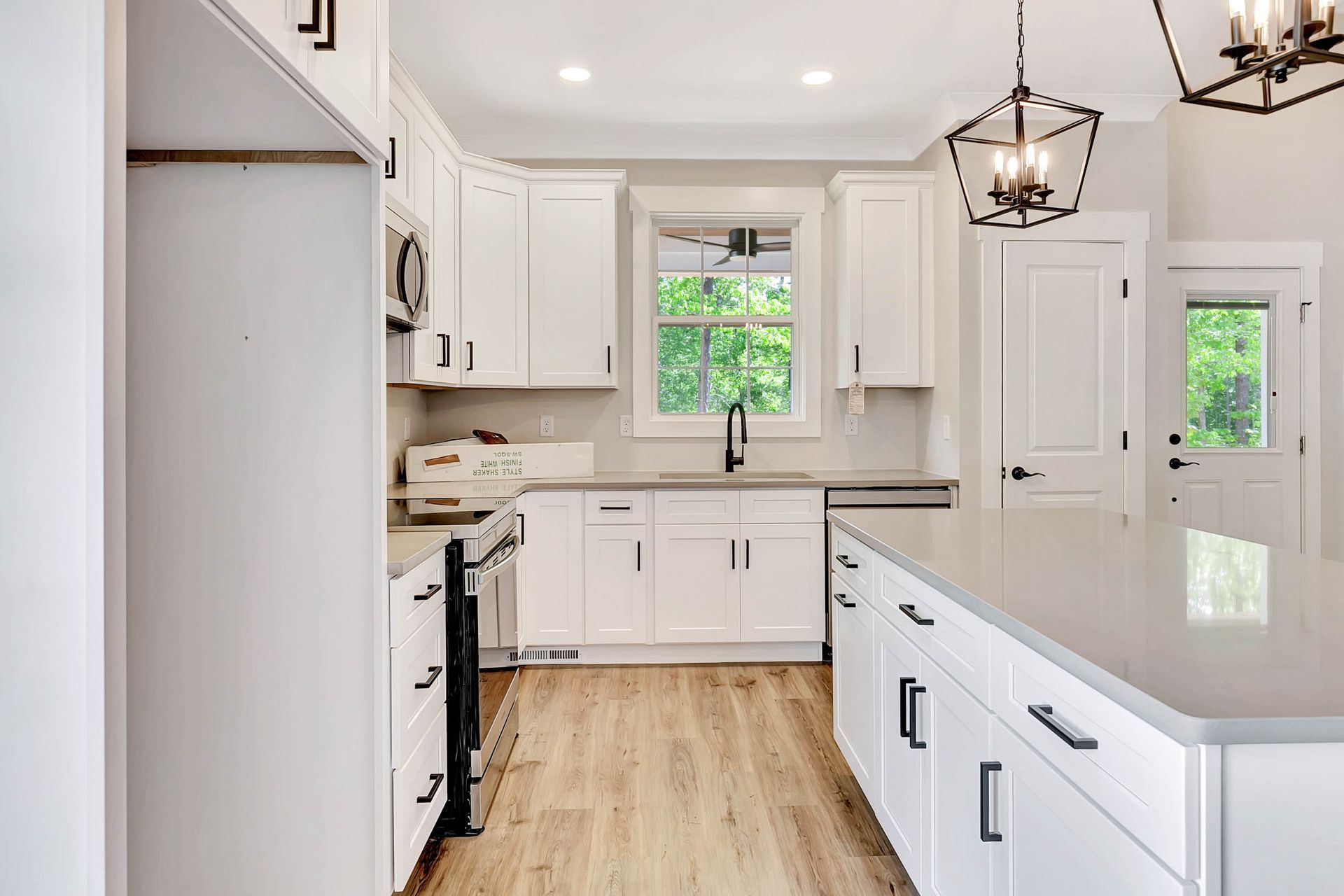 A kitchen with white cabinets , granite counter tops , stainless steel appliances , and a large island.
