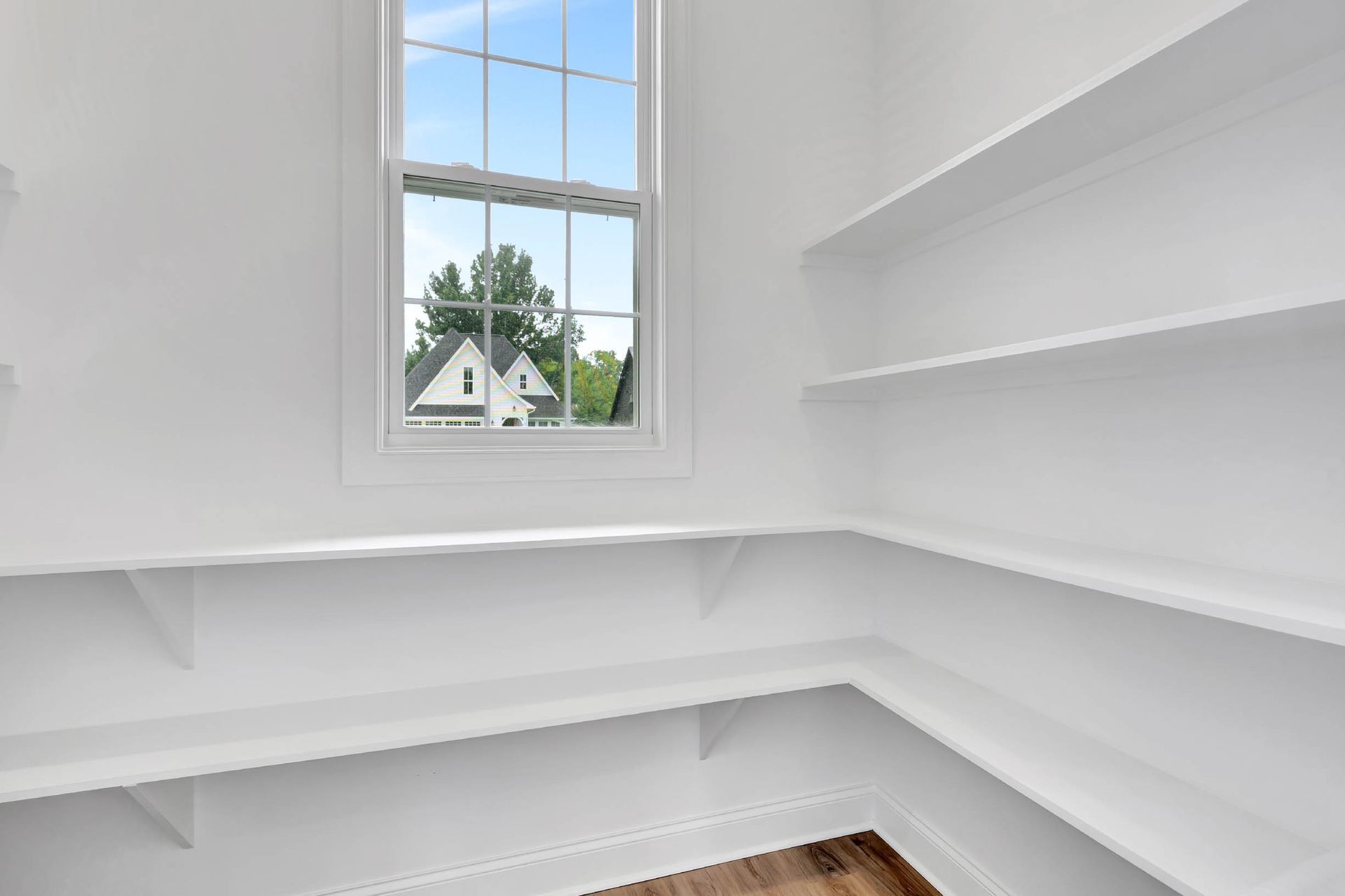 An empty room with white shelves and a window.