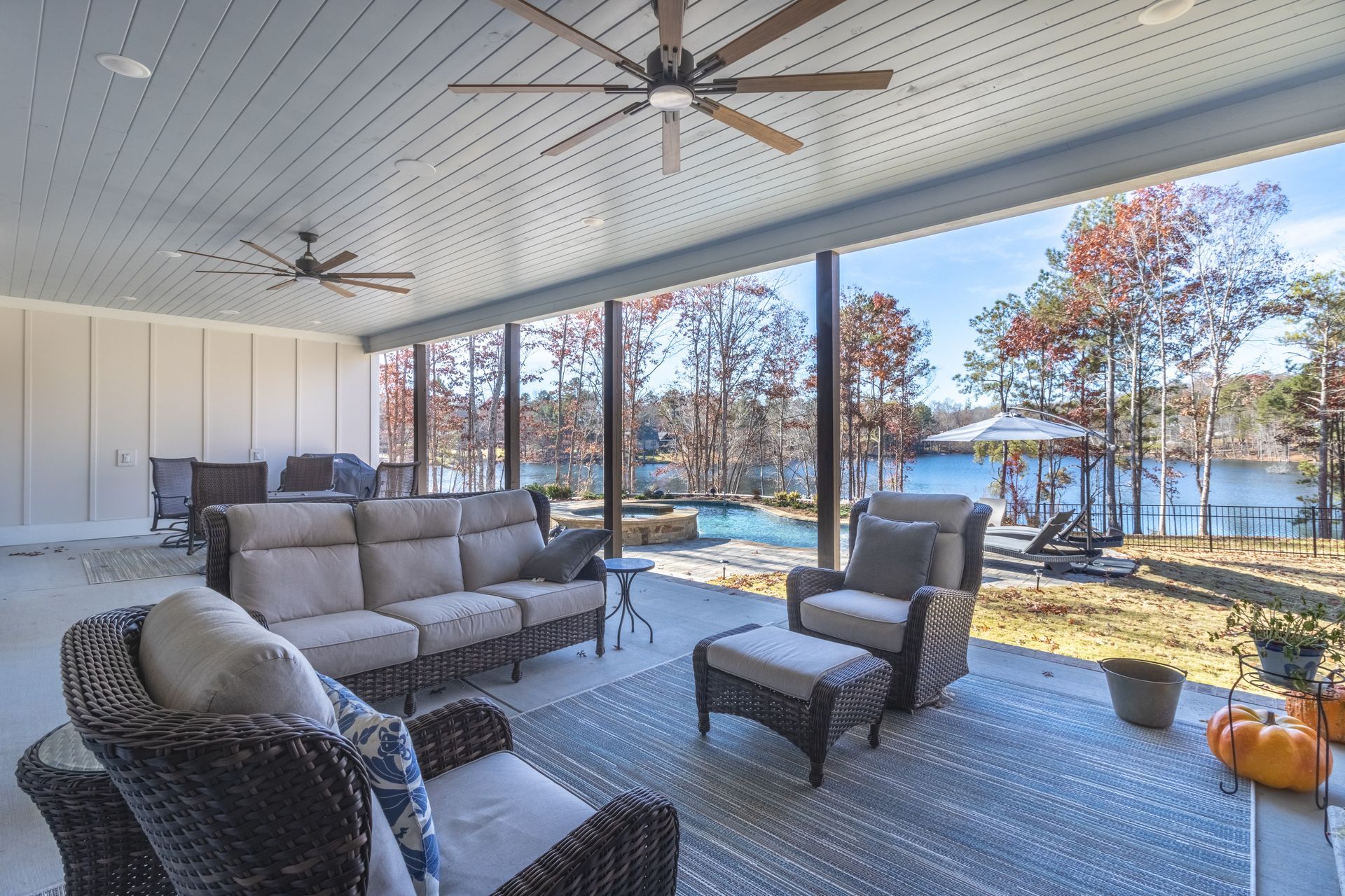 a patio with a couch , chairs and a ceiling fan overlooking a lake .