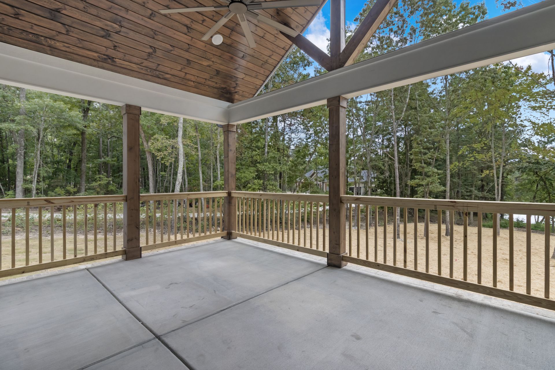 an empty porch with a wooden railing and a ceiling fan .