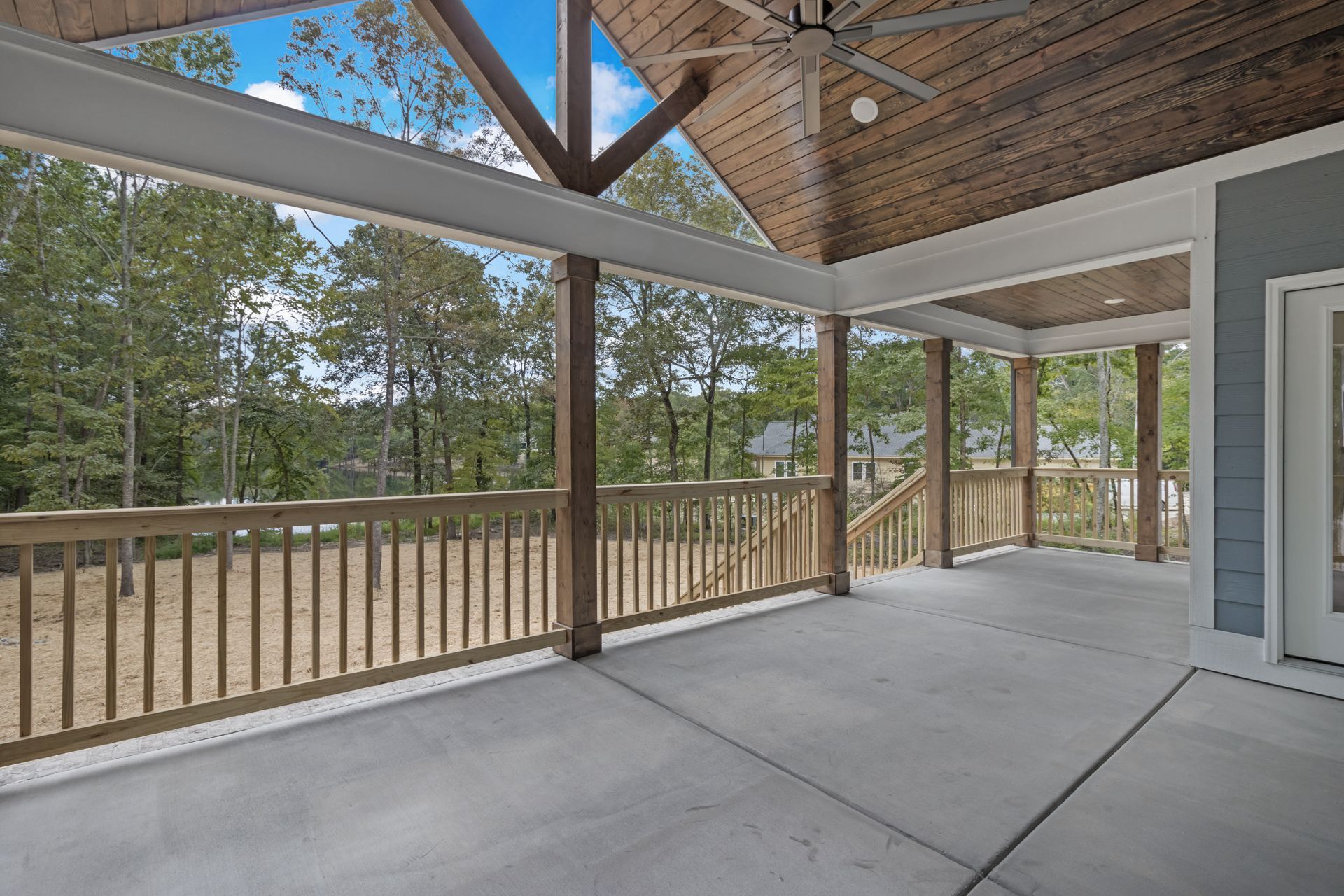 a large covered porch with a wooden railing and a ceiling fan .