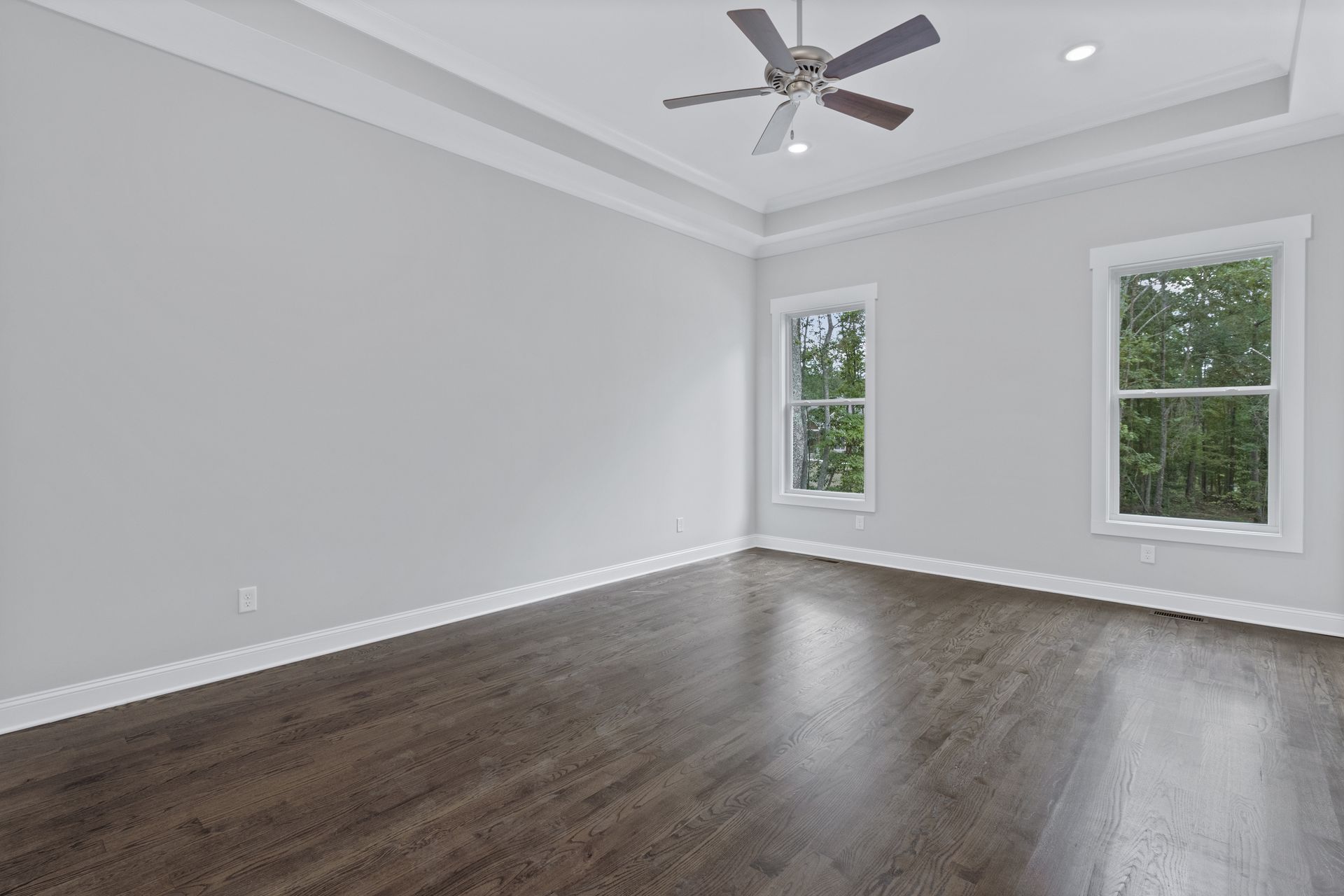 an empty room with hardwood floors and a ceiling fan .