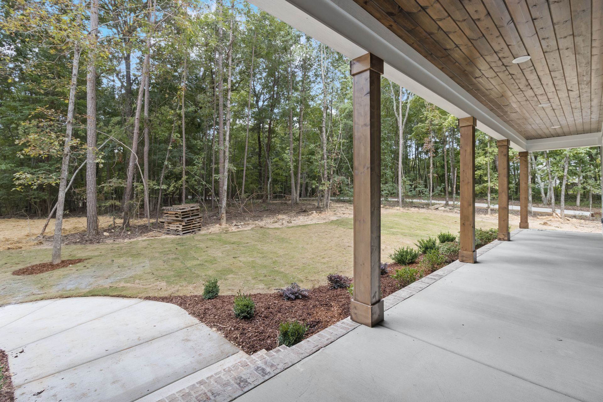 a covered porch with a view of a lush green forest .