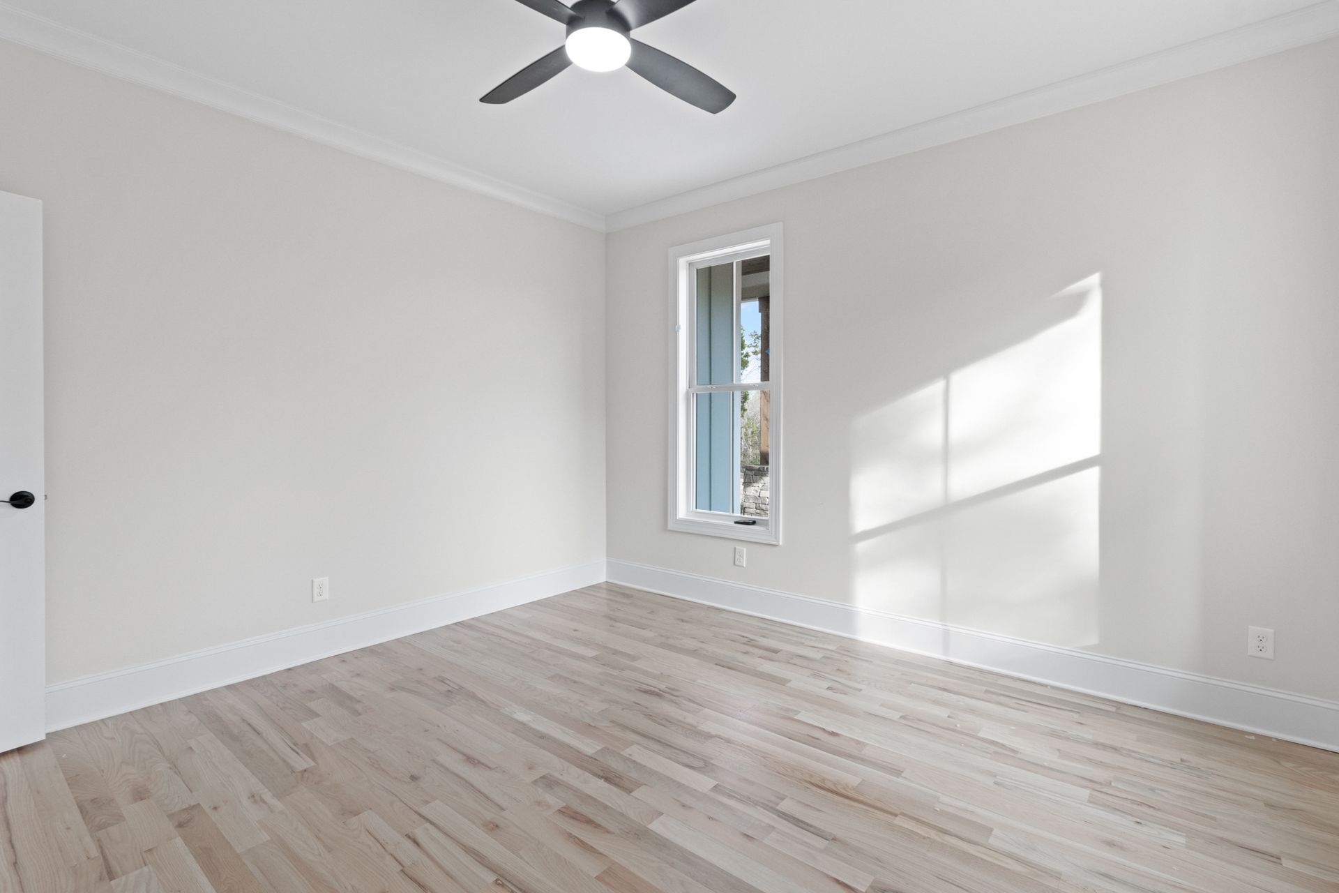 an empty bedroom with hardwood floors and a ceiling fan .