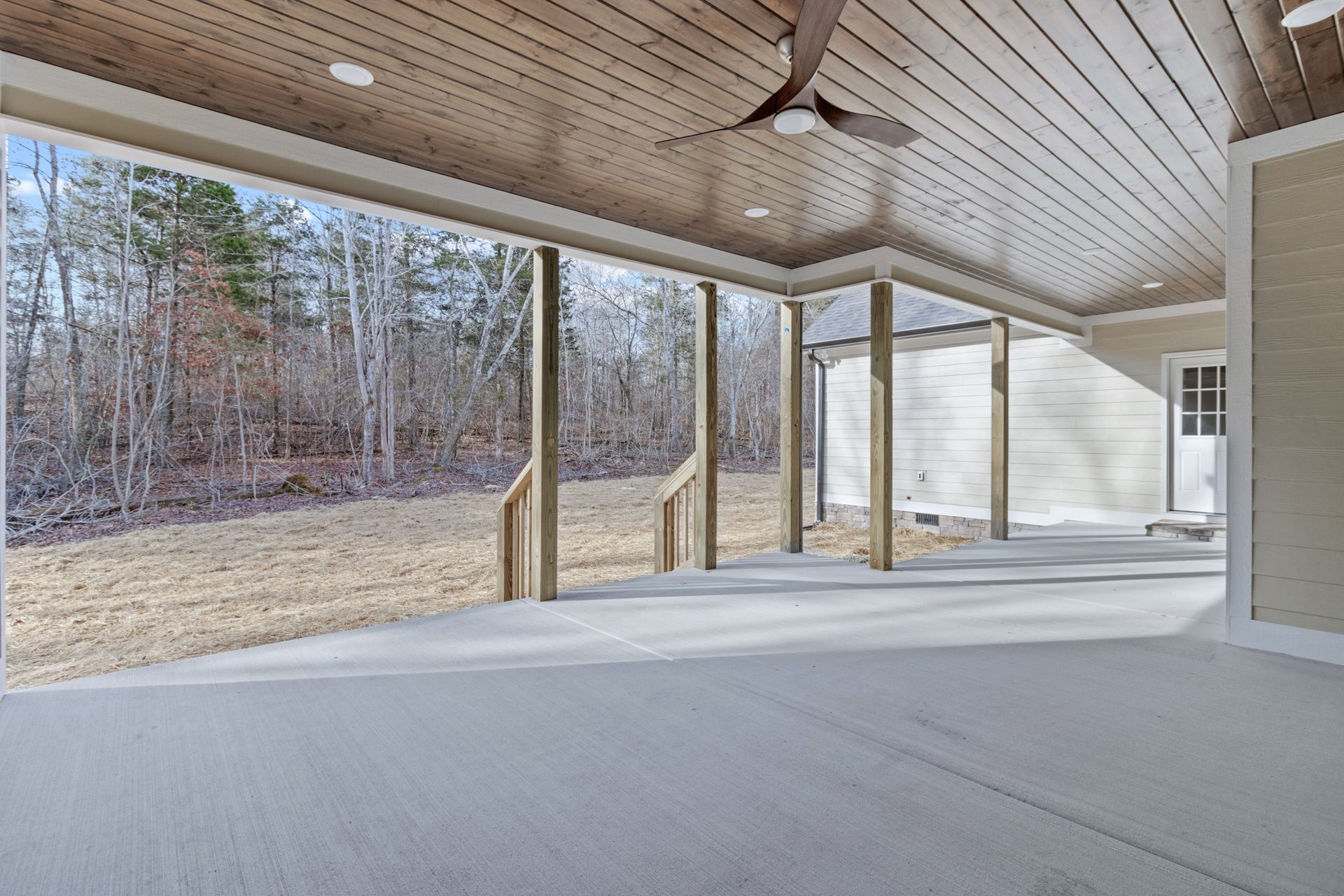 an empty patio with a ceiling fan and a view of the woods .