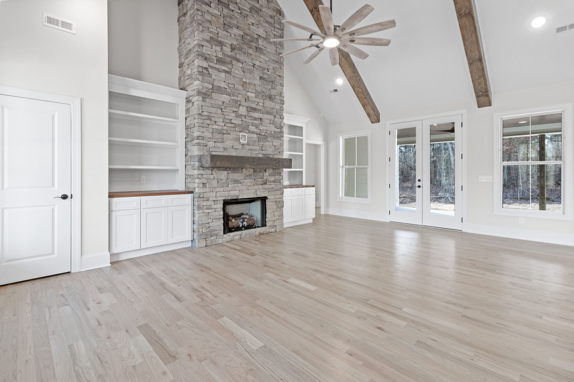 an empty living room with a fireplace and a ceiling fan .