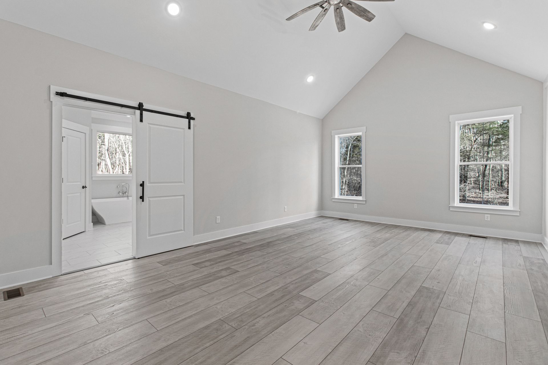 a large empty room with hardwood floors and a vaulted ceiling .
