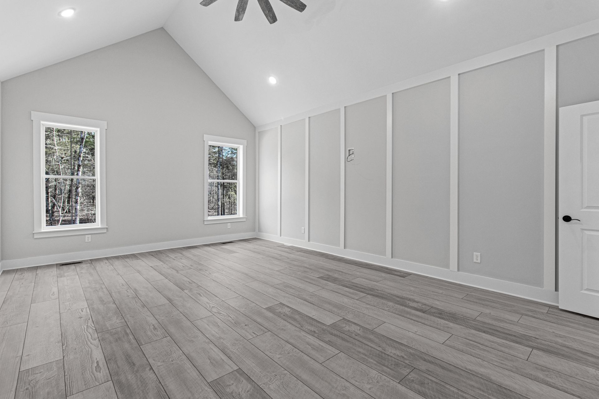 a large empty room with hardwood floors and a vaulted ceiling .