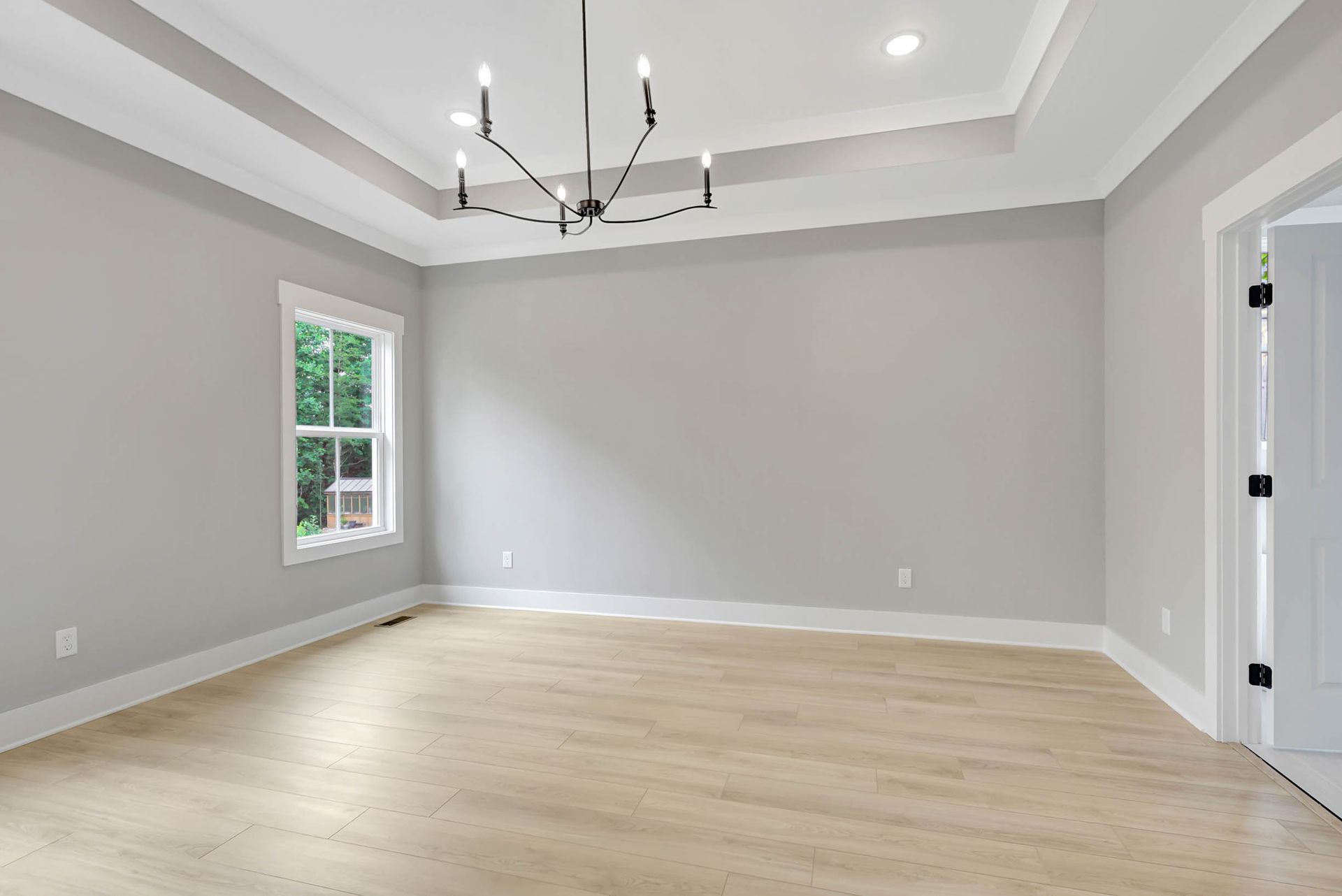 An empty room with a chandelier hanging from the ceiling and a window.