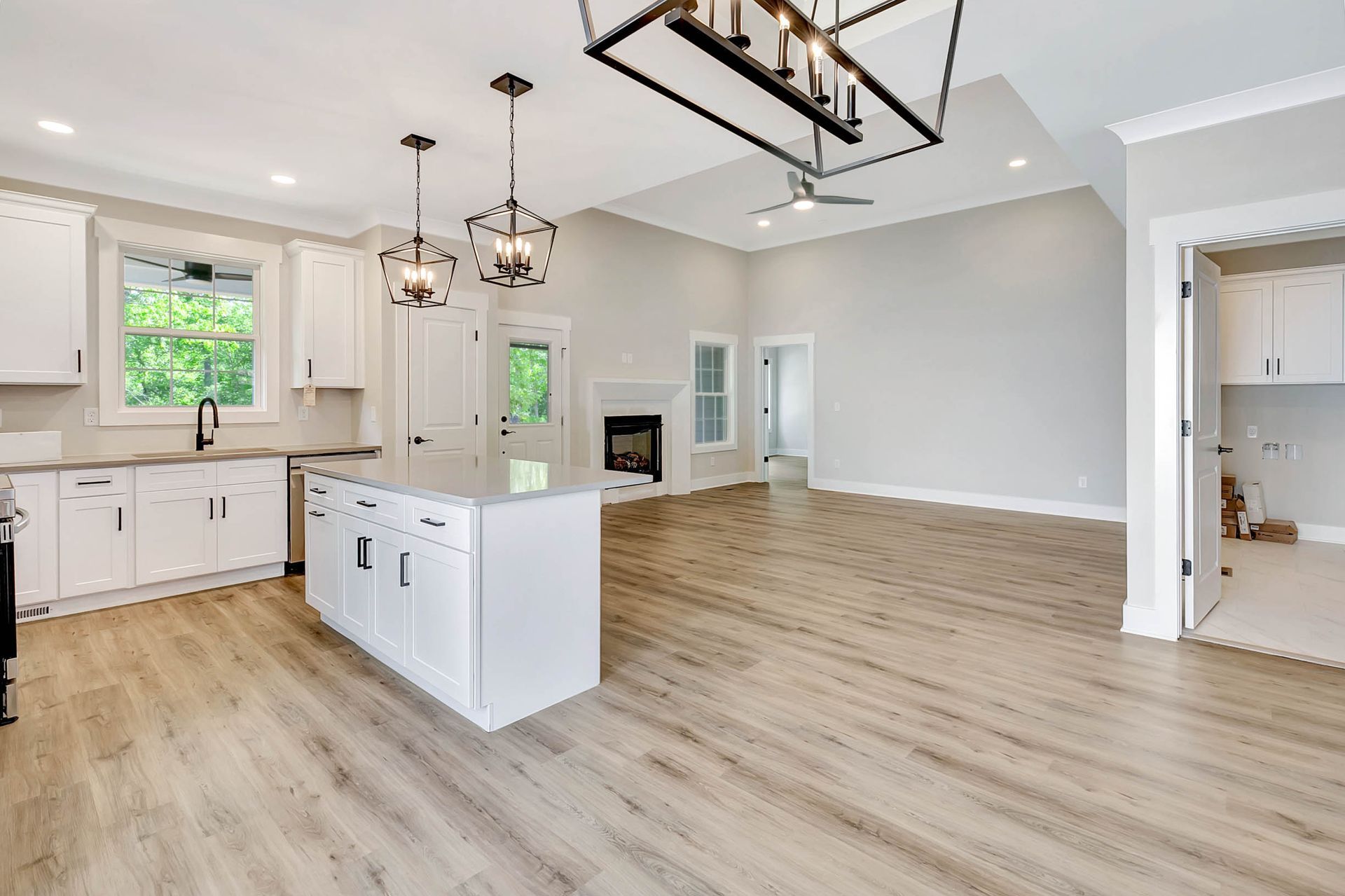 A kitchen and living room in a house with hardwood floors and white cabinets.