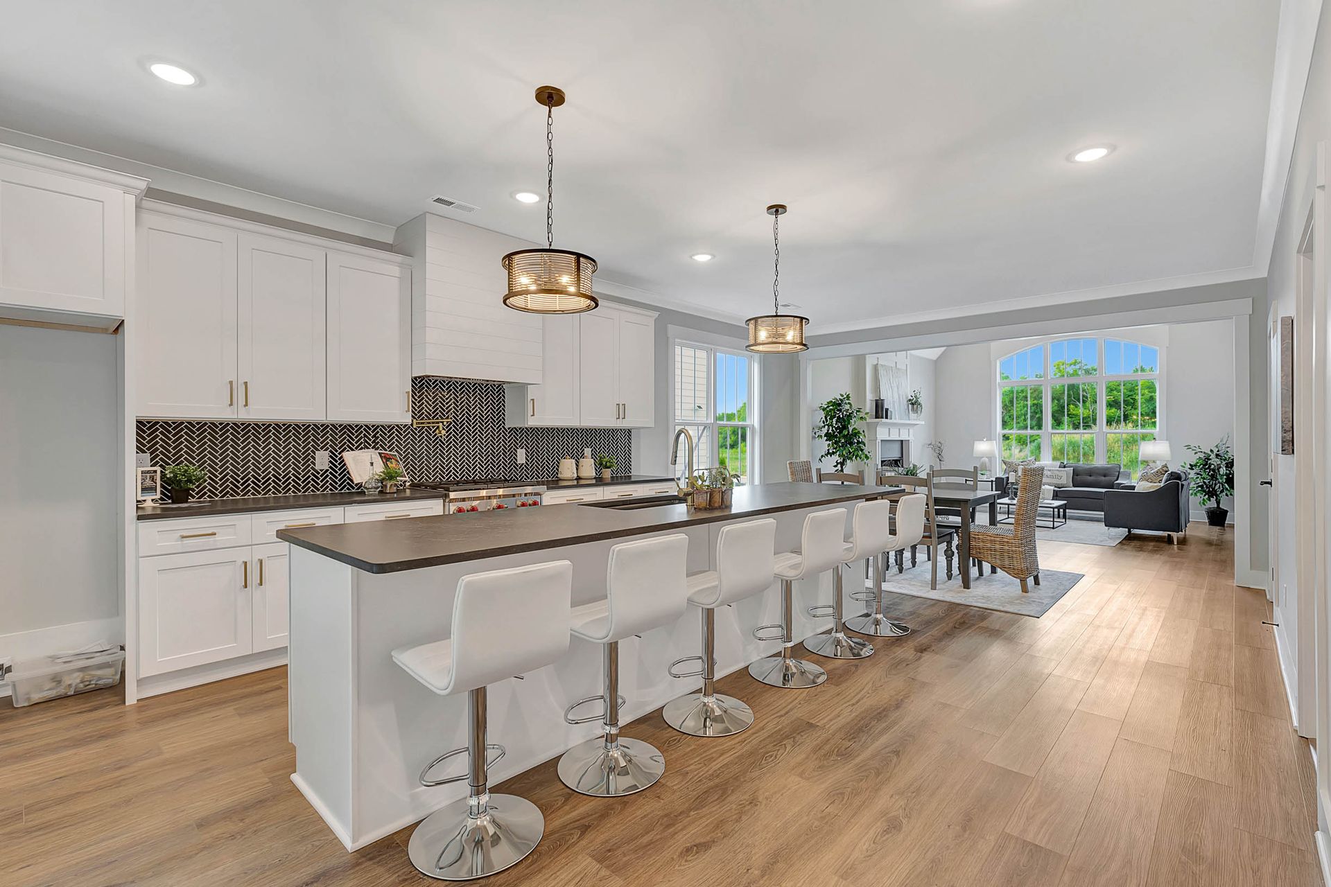 A kitchen with white cabinets , a large island , and stools.