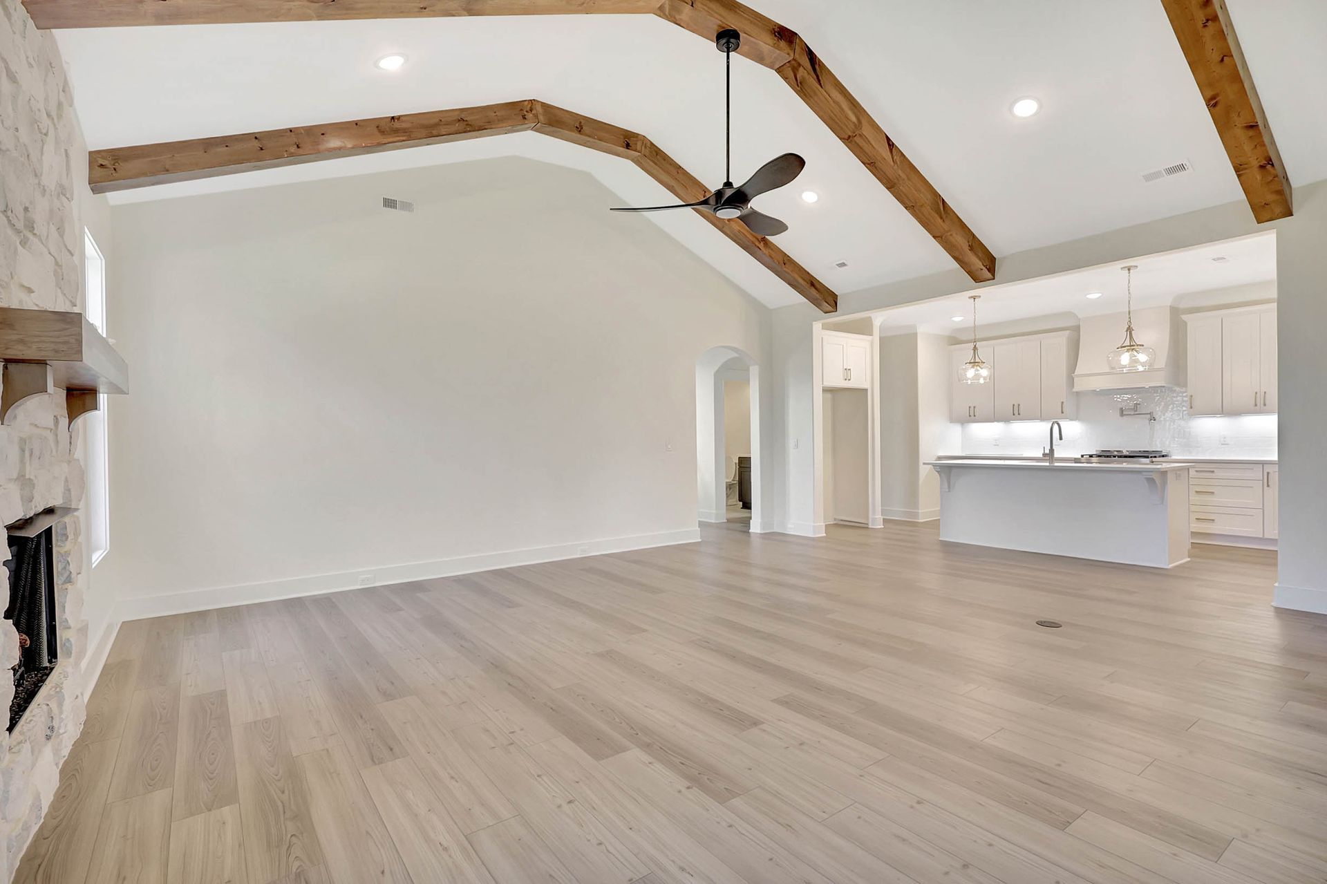 An empty living room with hardwood floors and a ceiling fan.