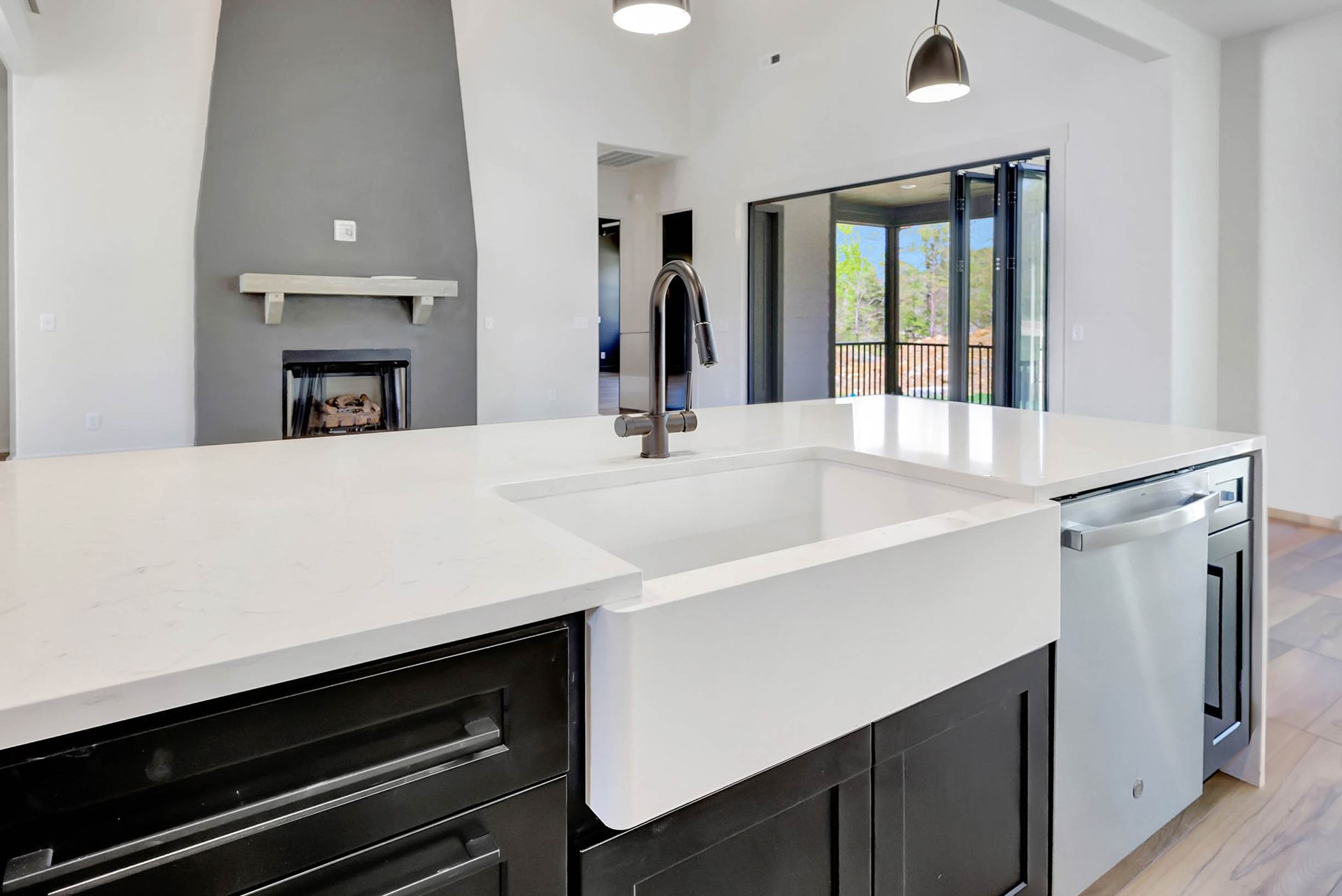 A kitchen with a large white sink and black cabinets.