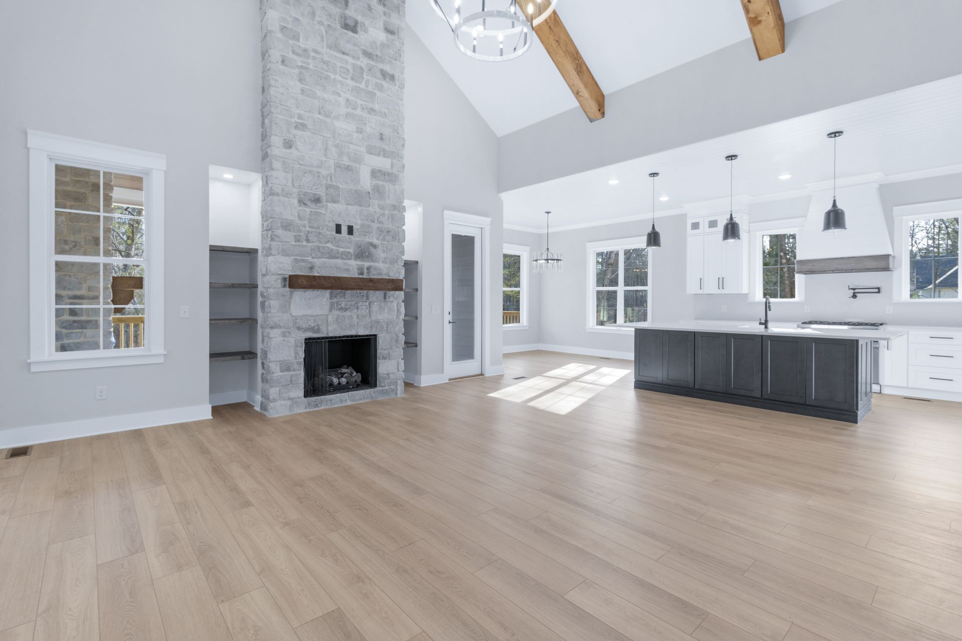 an empty living room with hardwood floors , a fireplace , and a kitchen .