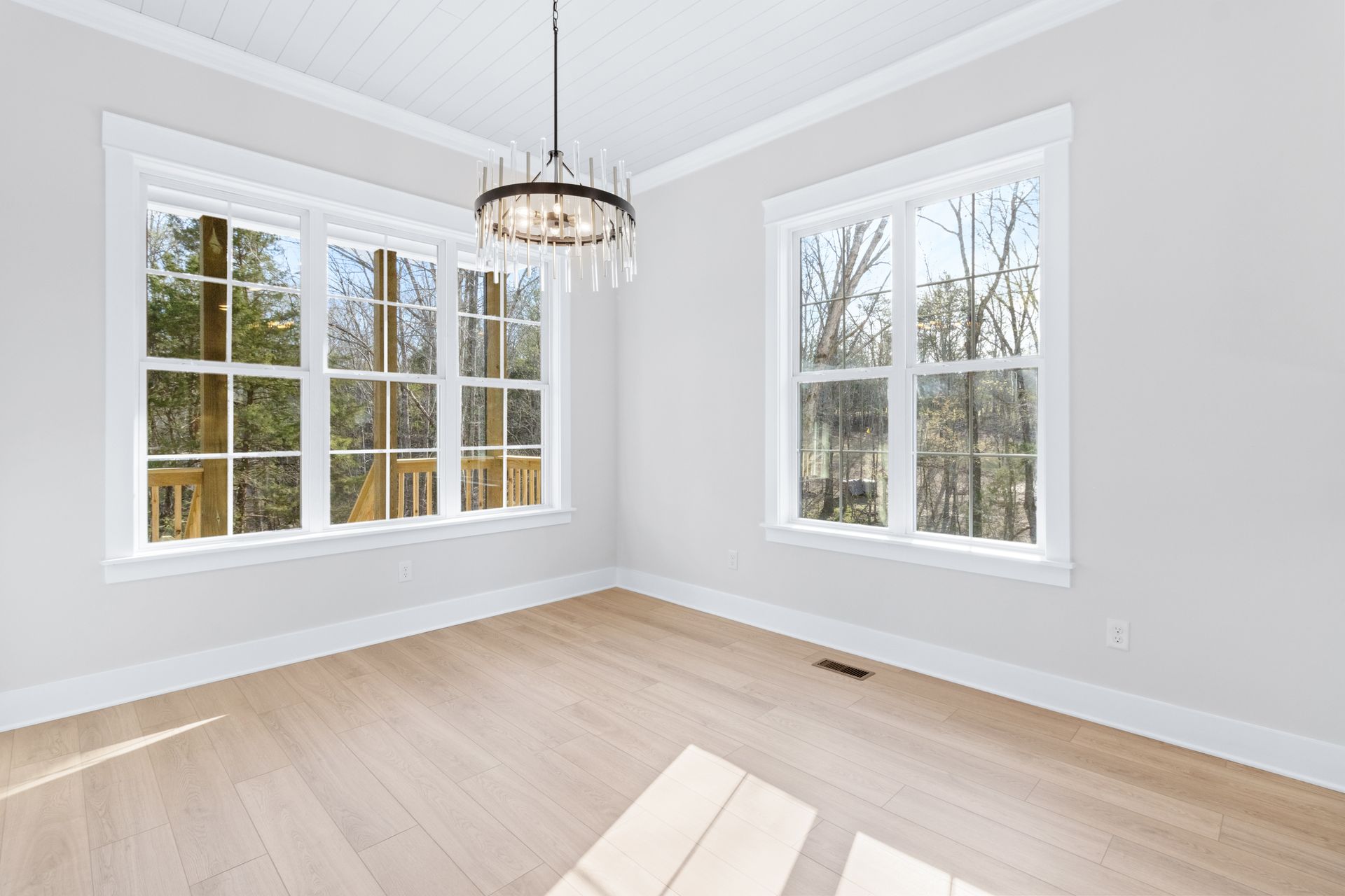 an empty room with lots of windows and a chandelier .