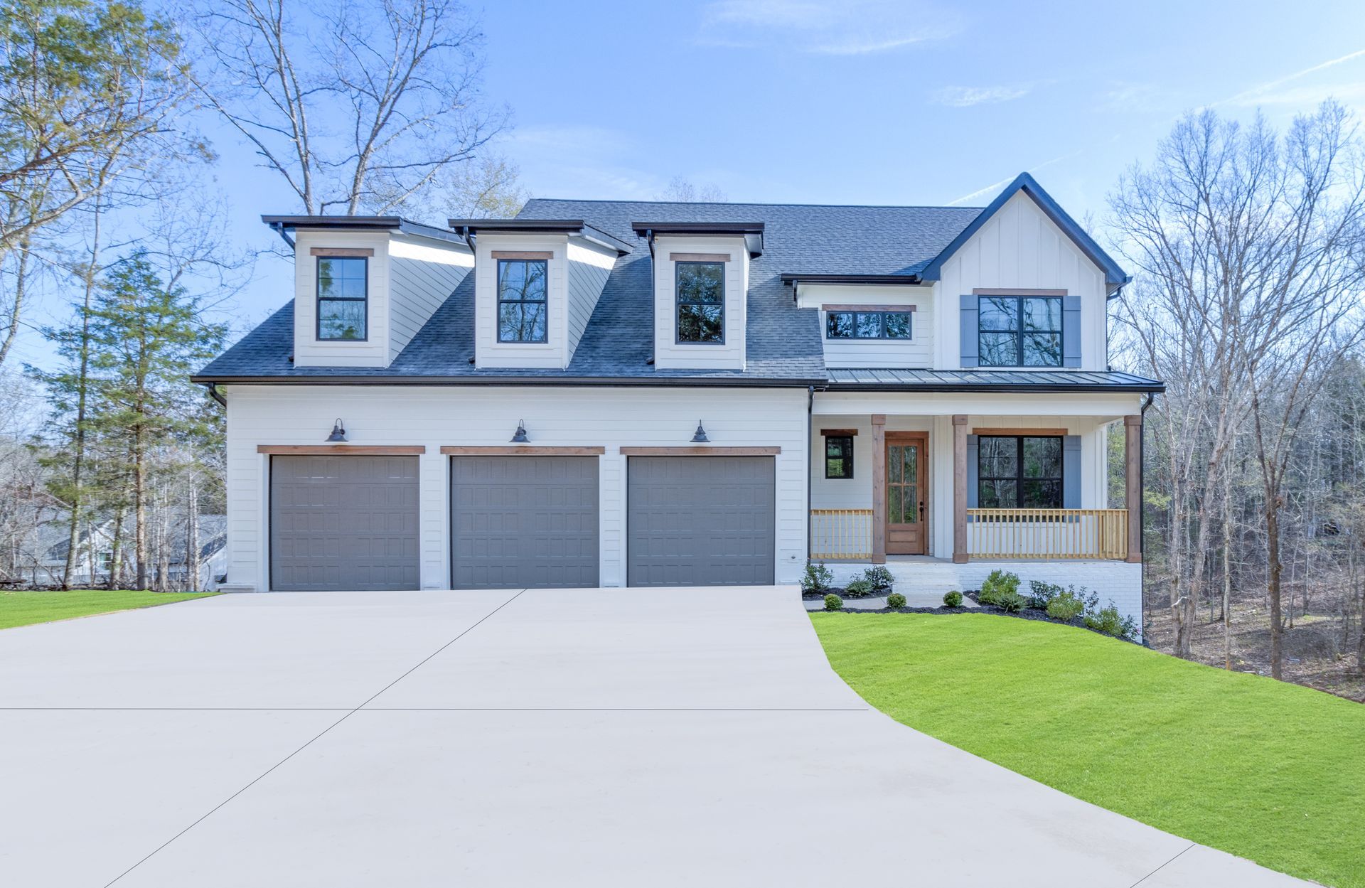 A large white house with three garage doors and a driveway.