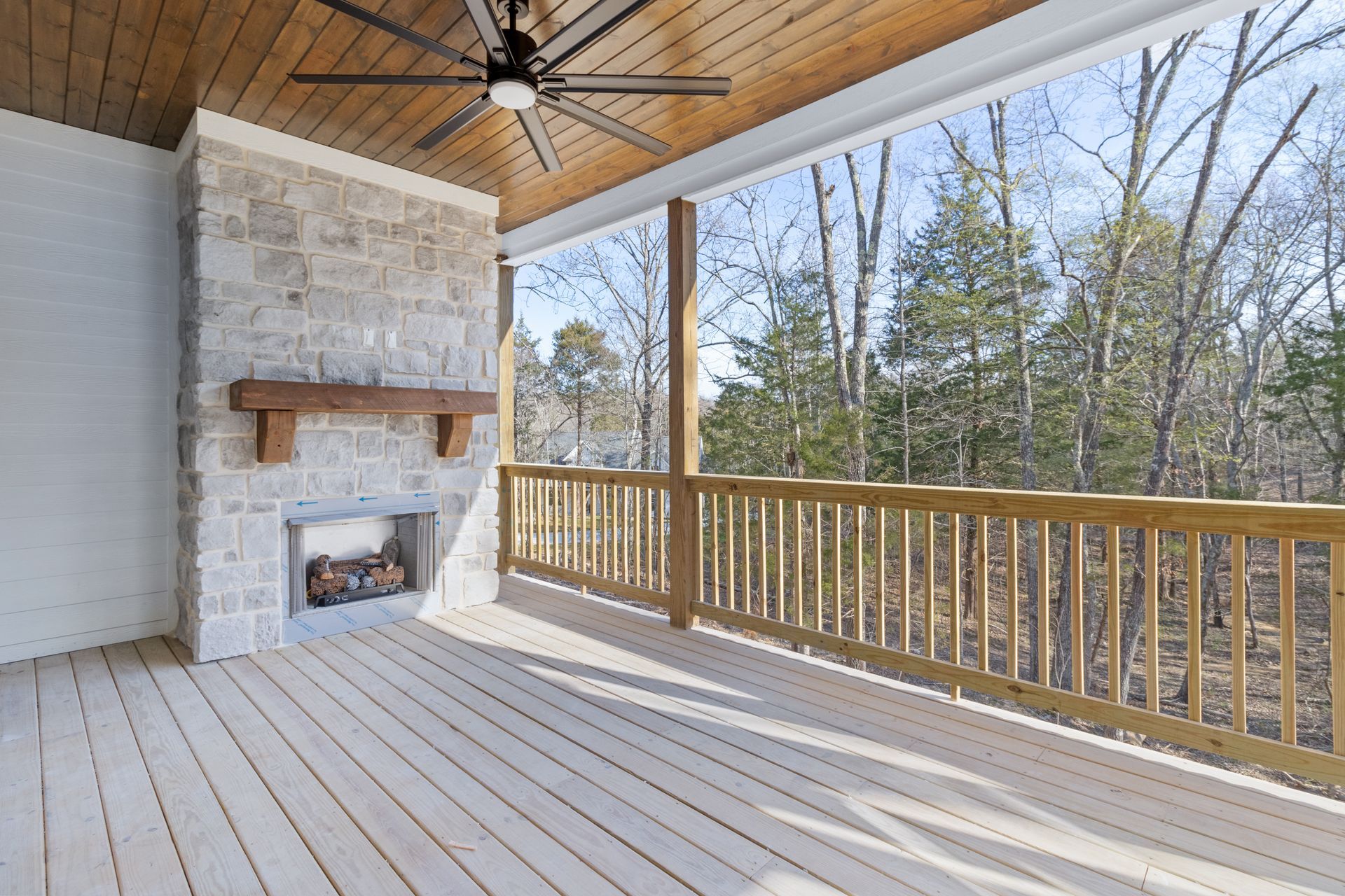 an empty deck with a fireplace and a ceiling fan .