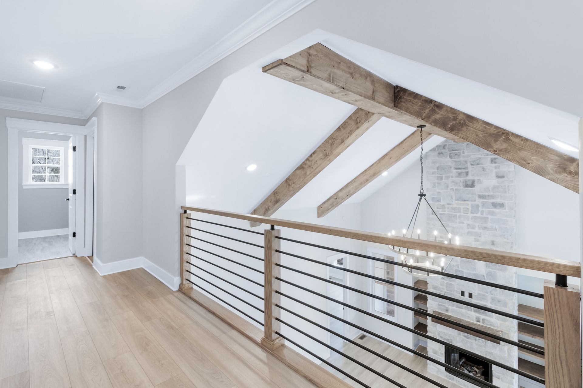 an empty hallway with a wooden railing and a chandelier hanging from the ceiling .
