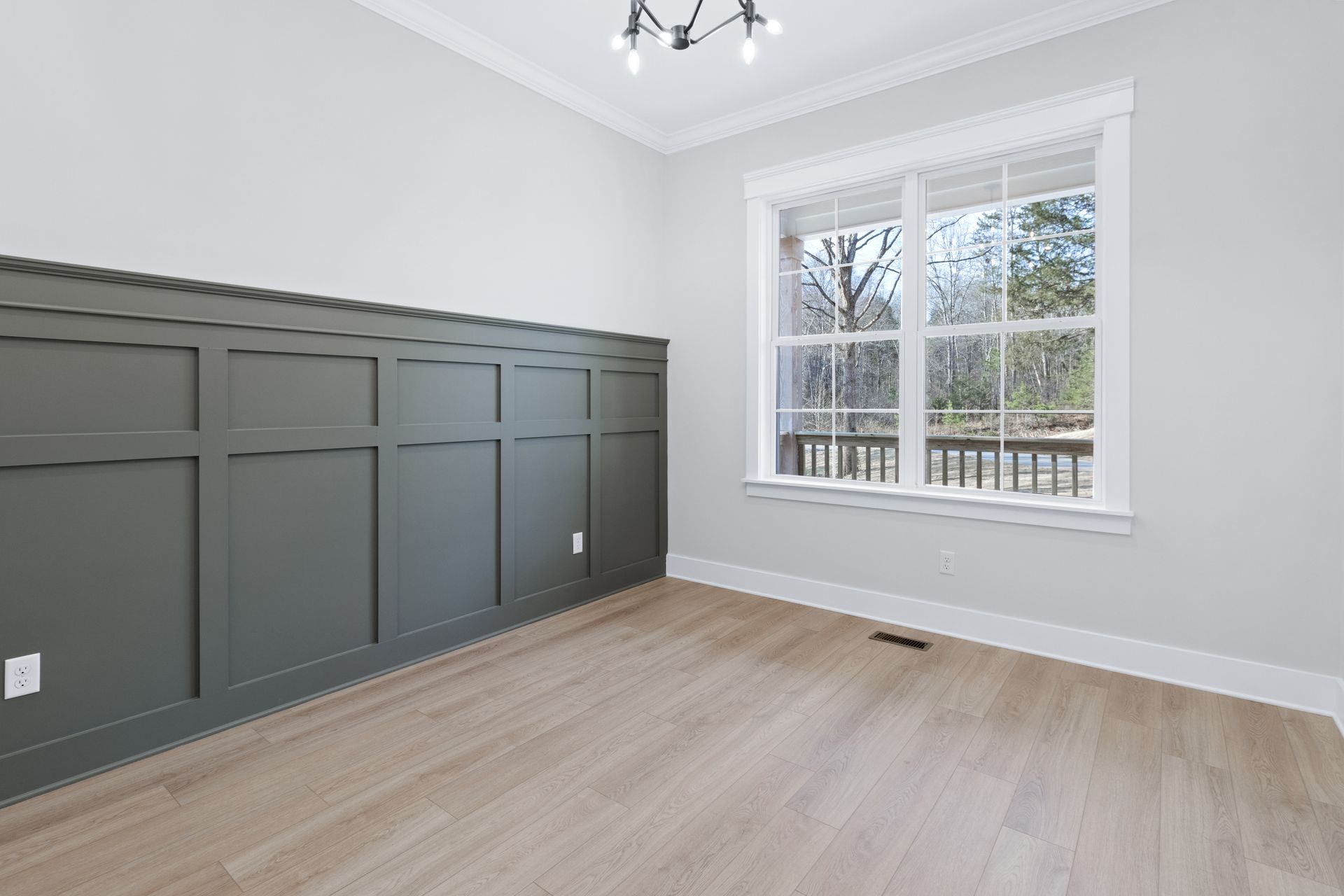 an empty room with a wooden floor and two windows .