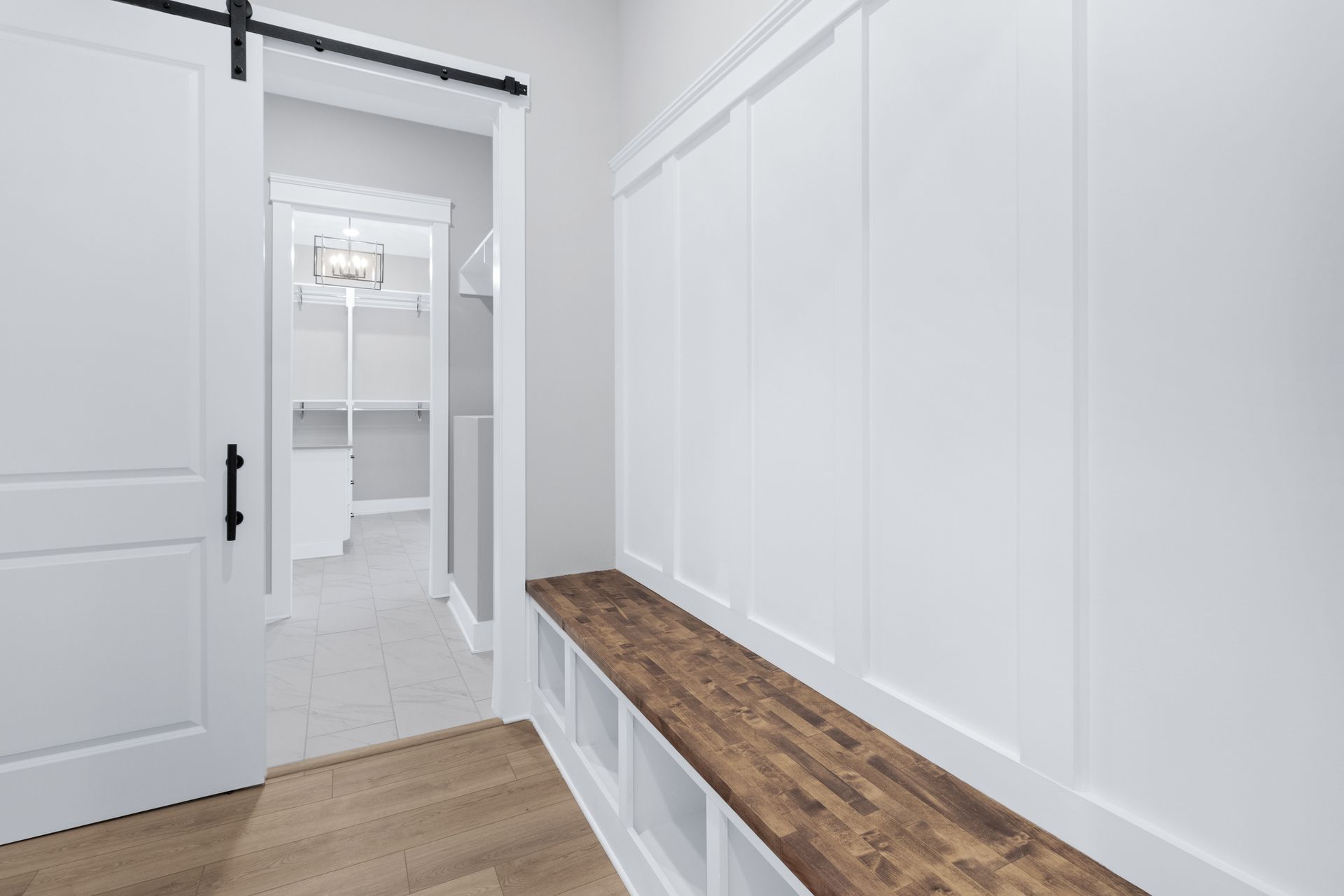 a hallway with a wooden bench and a sliding barn door leading to a bathroom .