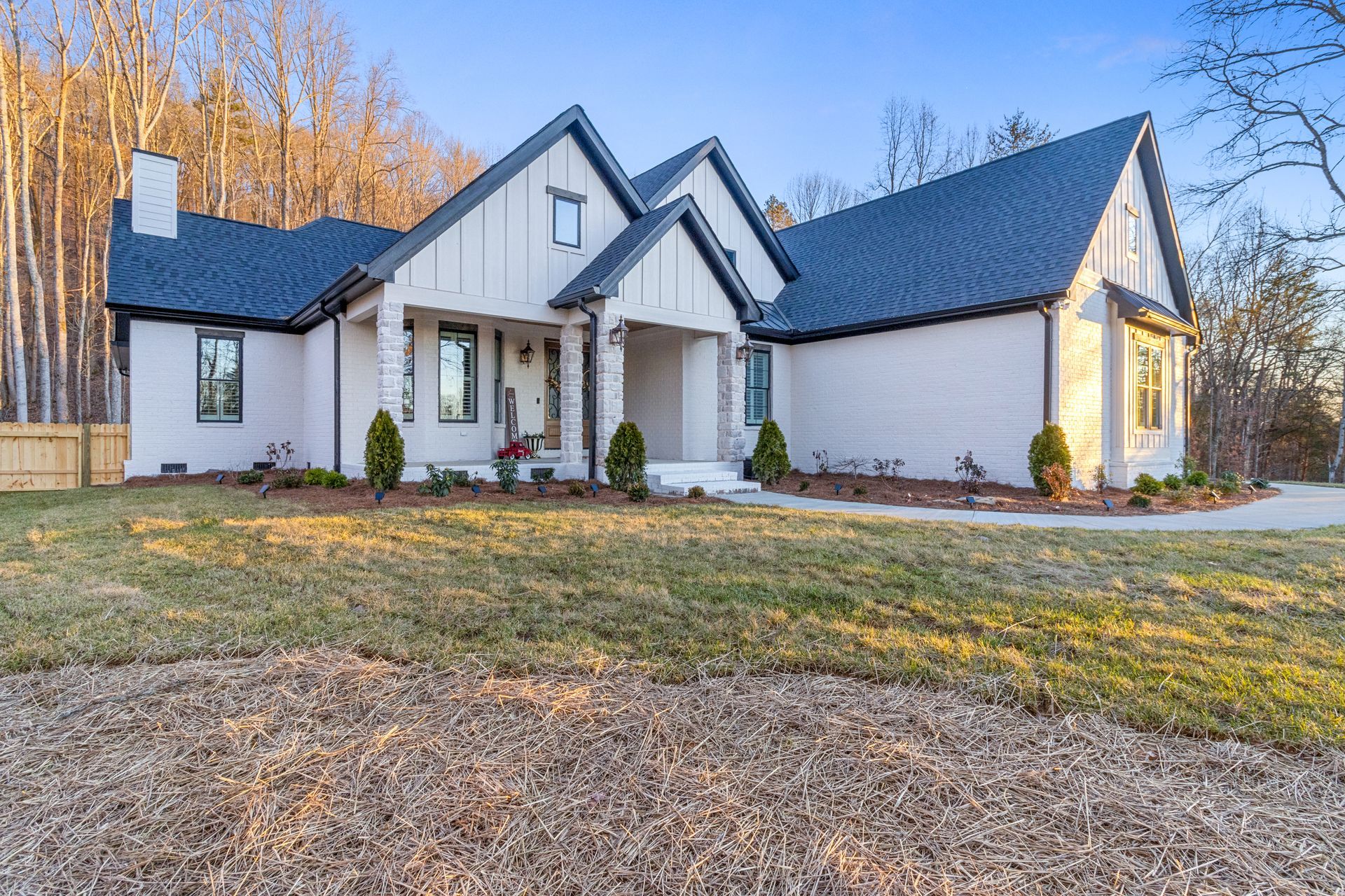 a large white house with a black roof is sitting on top of a lush green field .