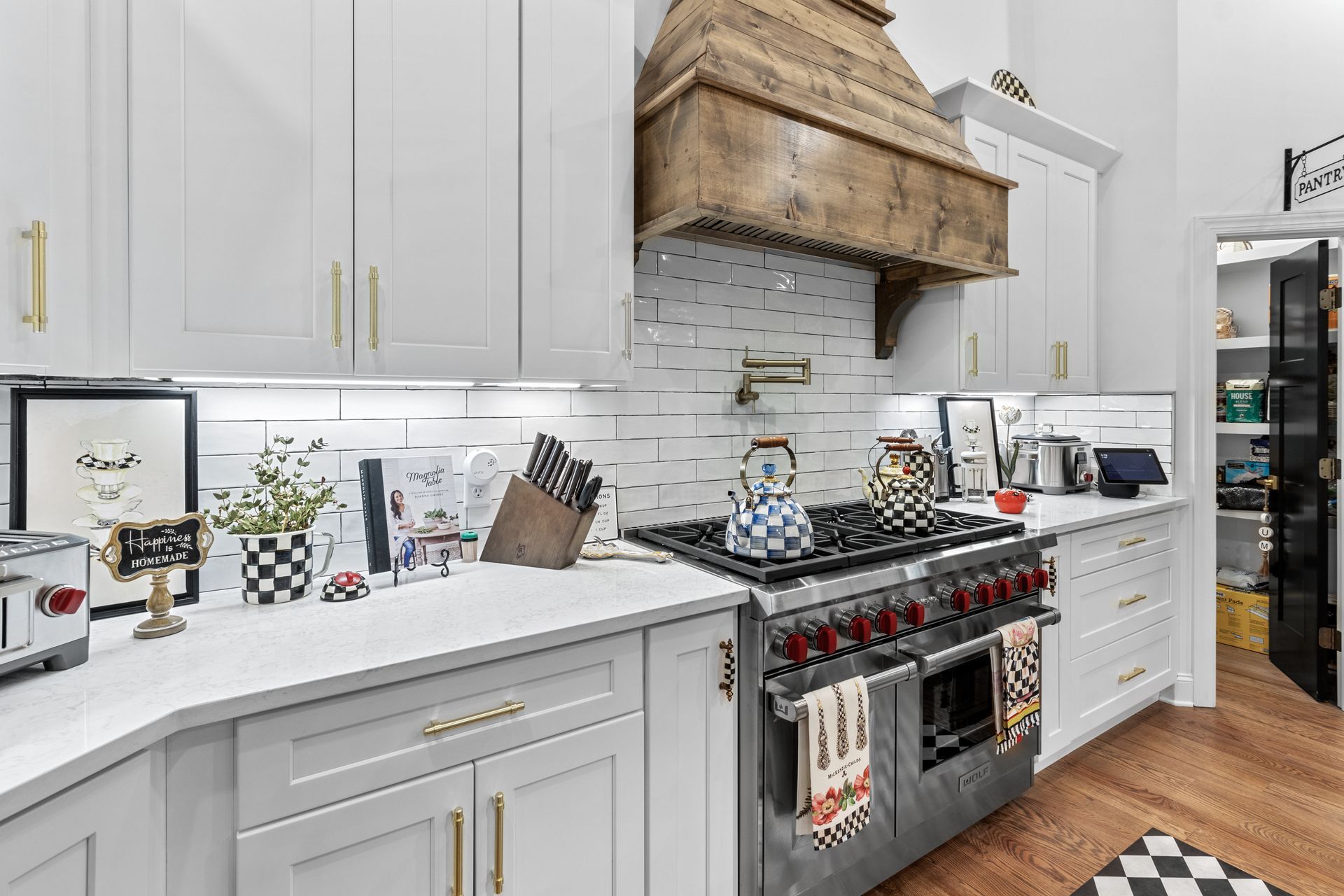 a kitchen with white cabinets , stainless steel appliances , and a wooden hood .