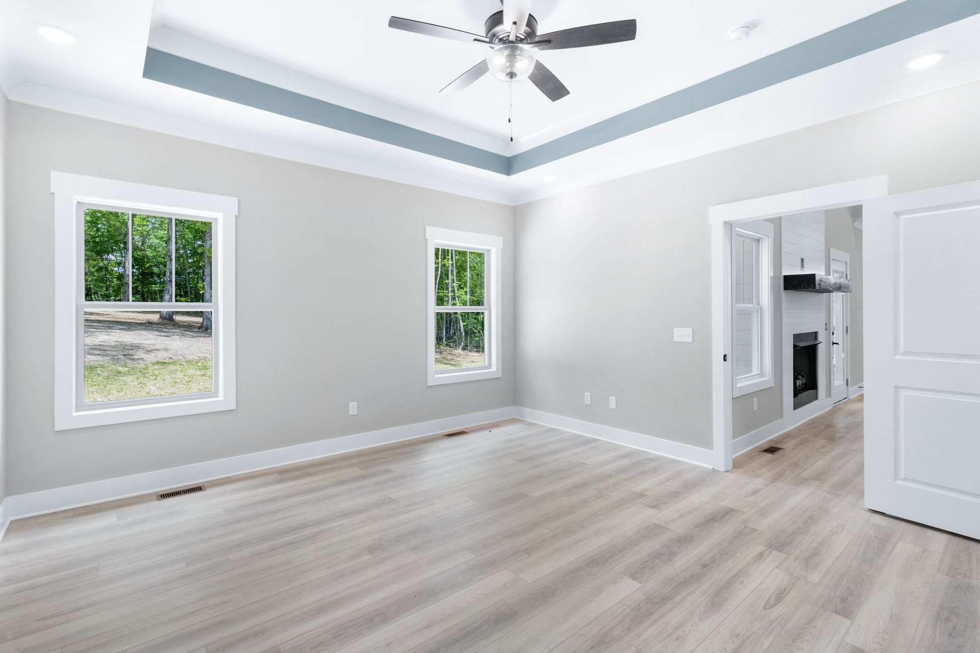 an empty living room with hardwood floors and a ceiling fan .