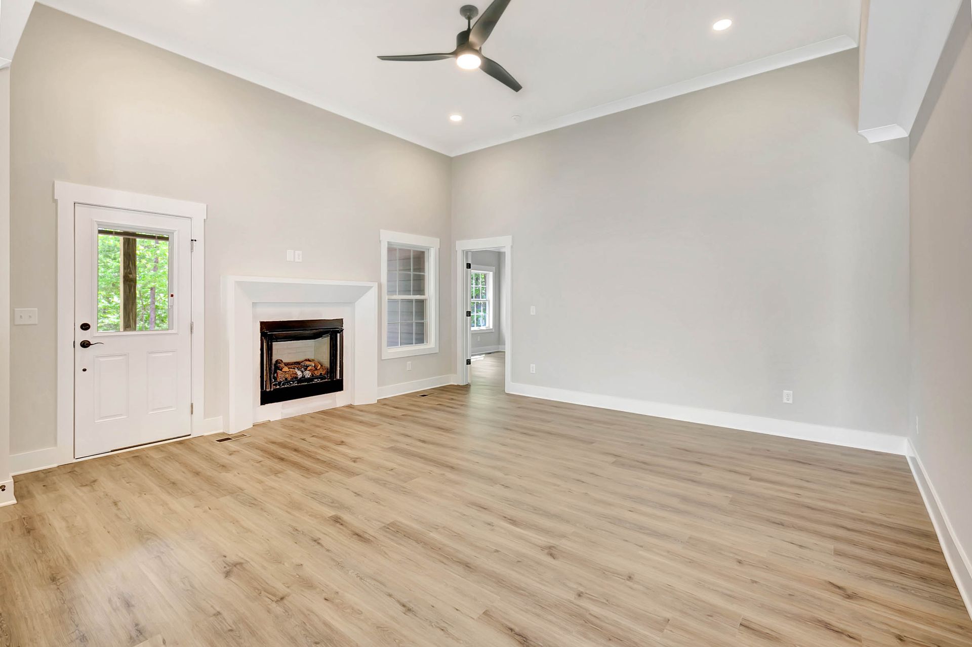 An empty living room with a fireplace and a ceiling fan.