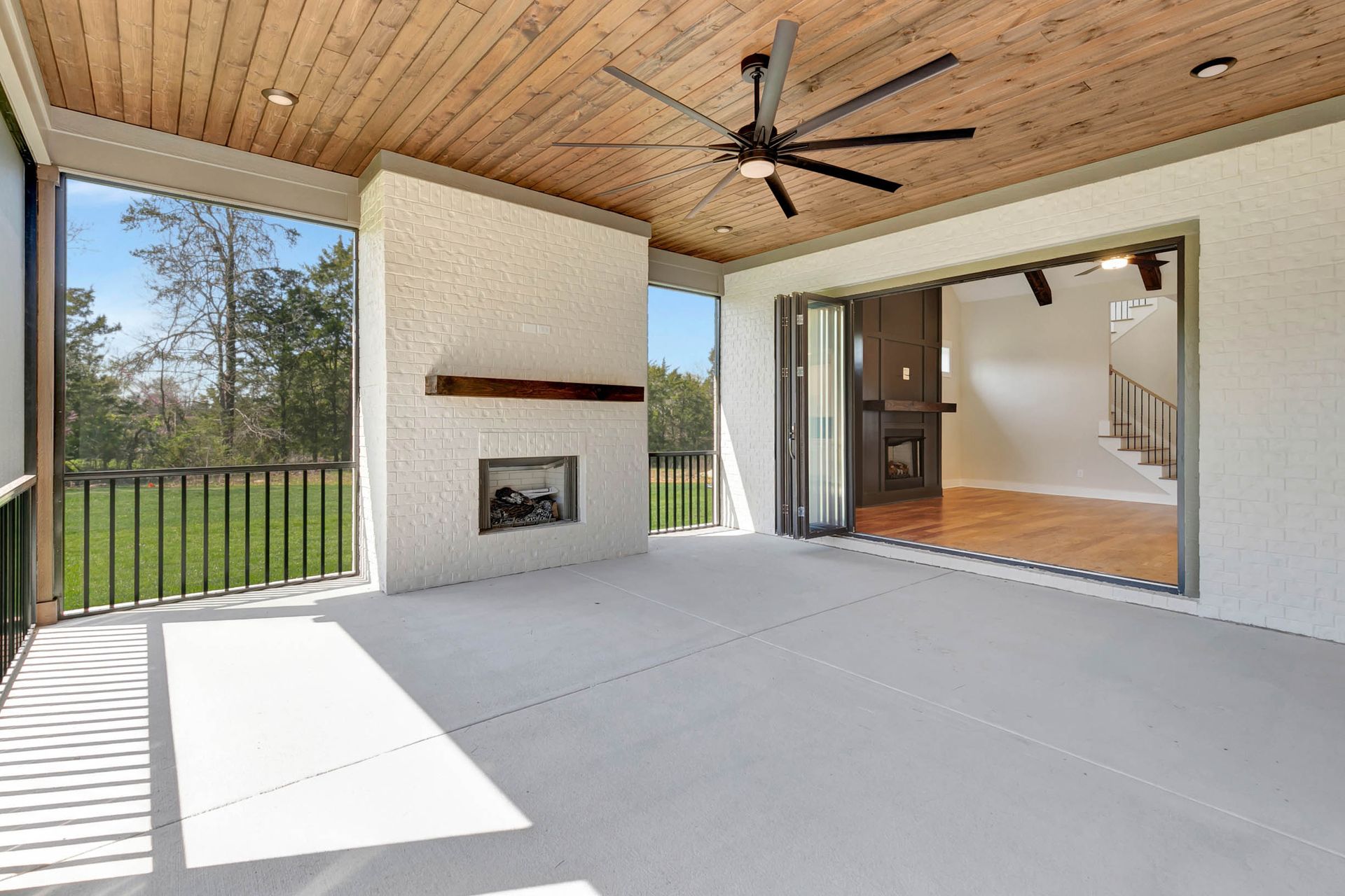 A large patio with a fireplace and a ceiling fan.