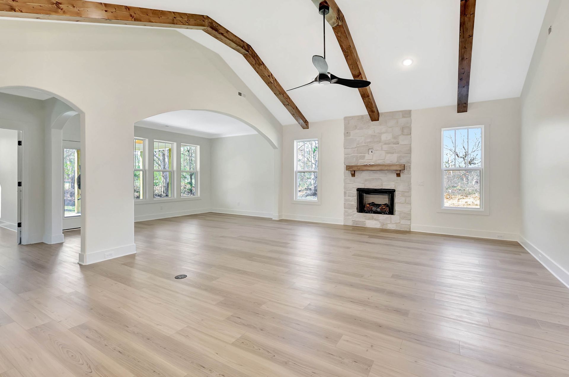 An empty living room with hardwood floors and a fireplace.