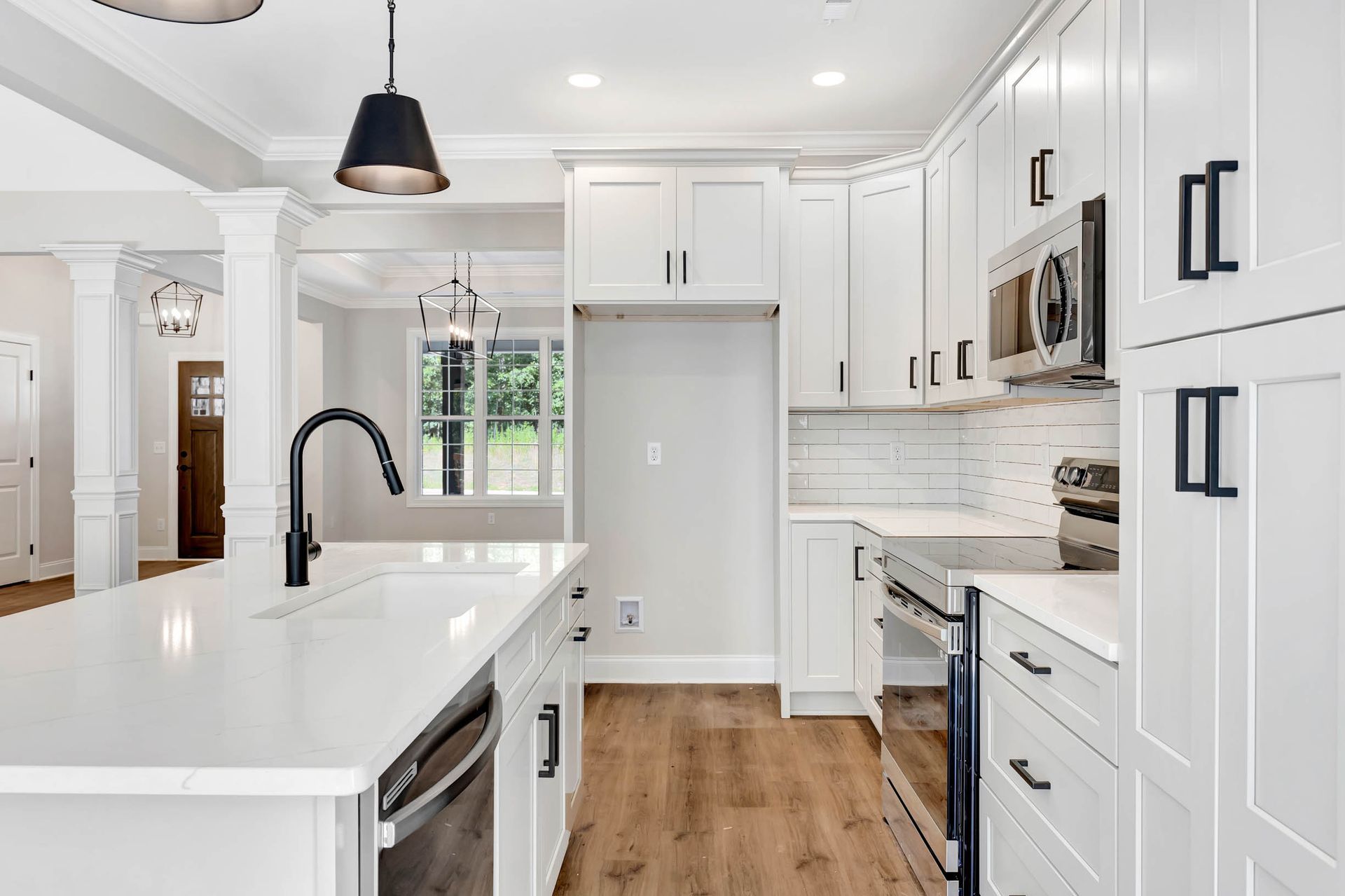A kitchen with white cabinets , stainless steel appliances , and a large island.