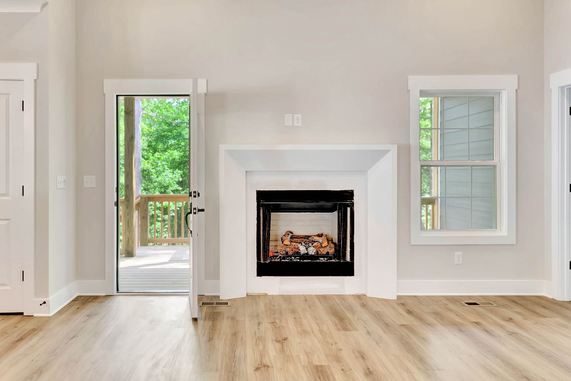 An empty living room with a fireplace and hardwood floors.