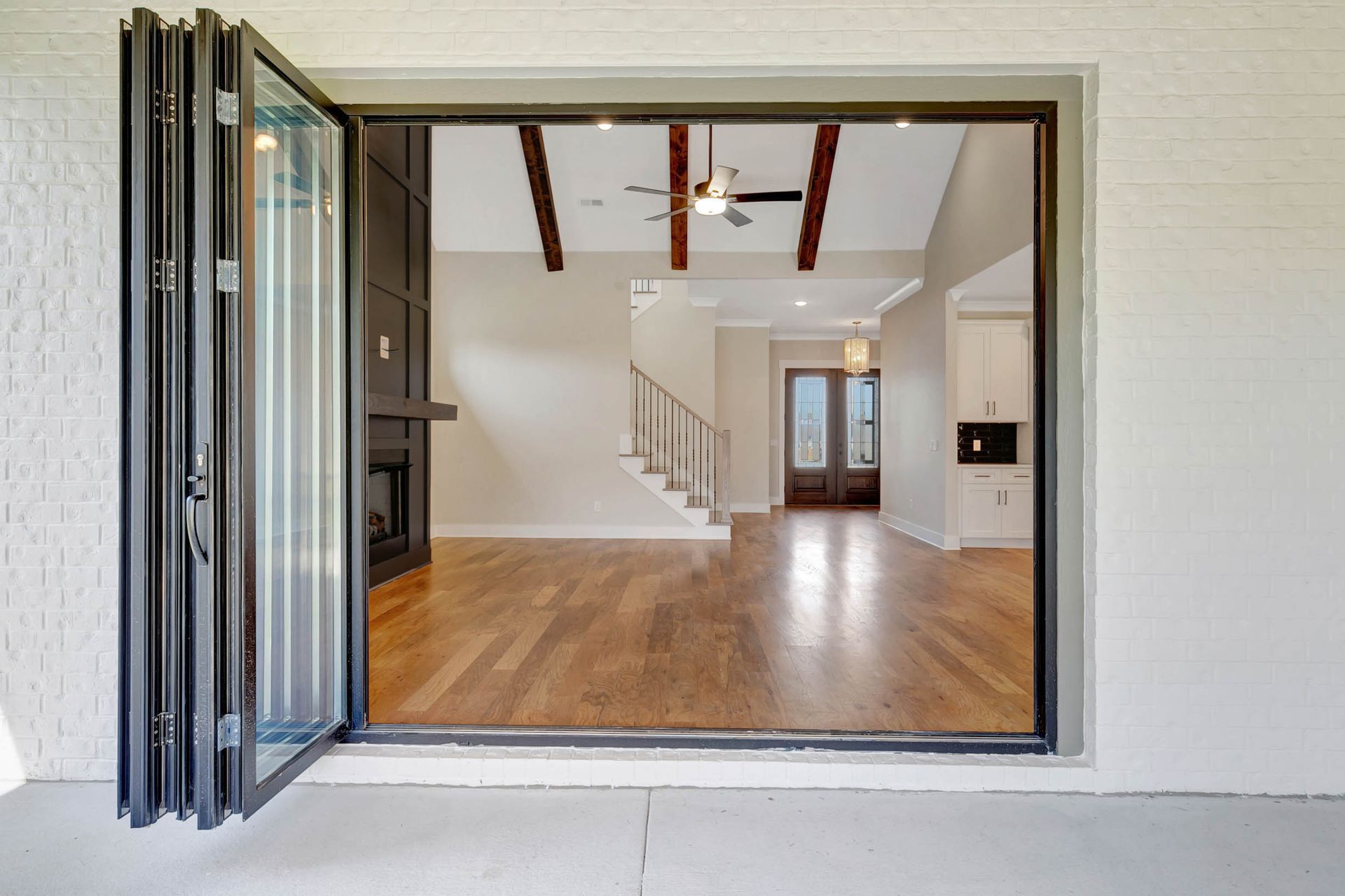 A sliding glass door open to a living room with hardwood floors