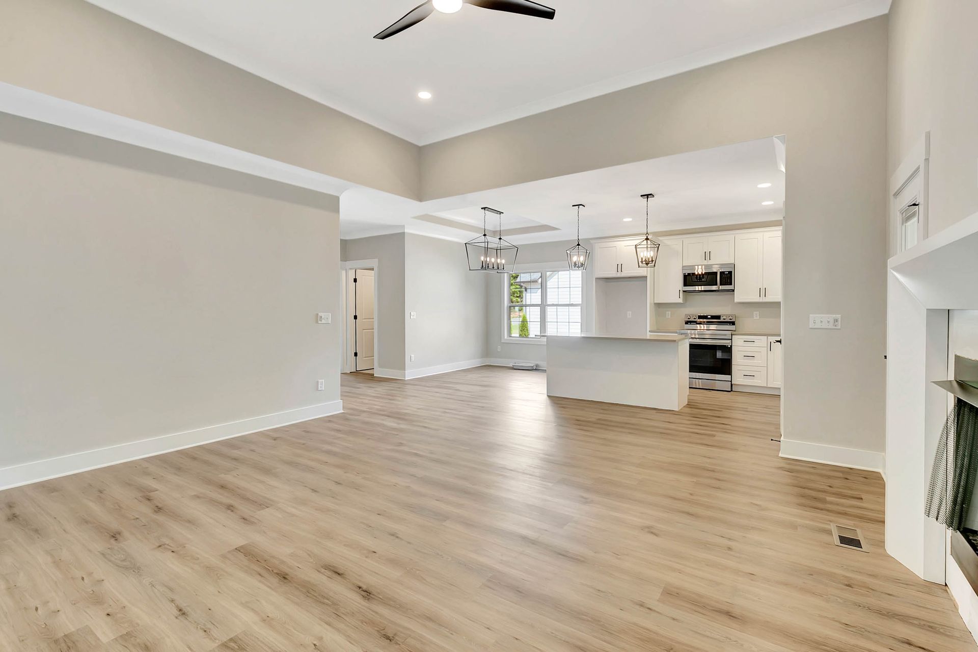 There is a ceiling fan in the living room and a kitchen in the background.