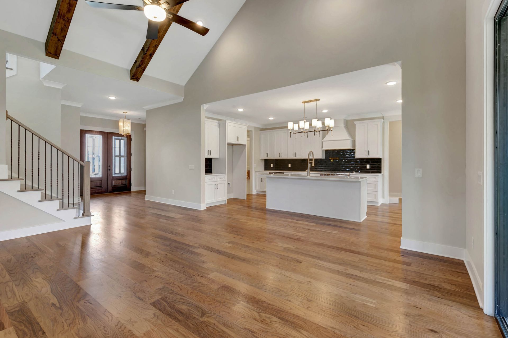 A kitchen and living room in a house with hardwood floors and a ceiling fan.