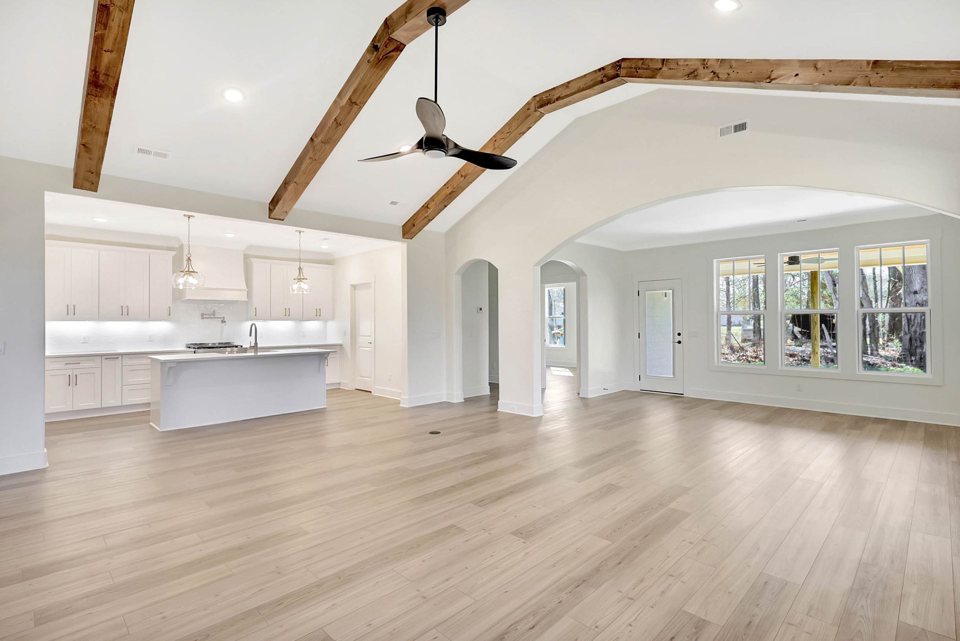 An empty living room with hardwood floors and a ceiling fan.