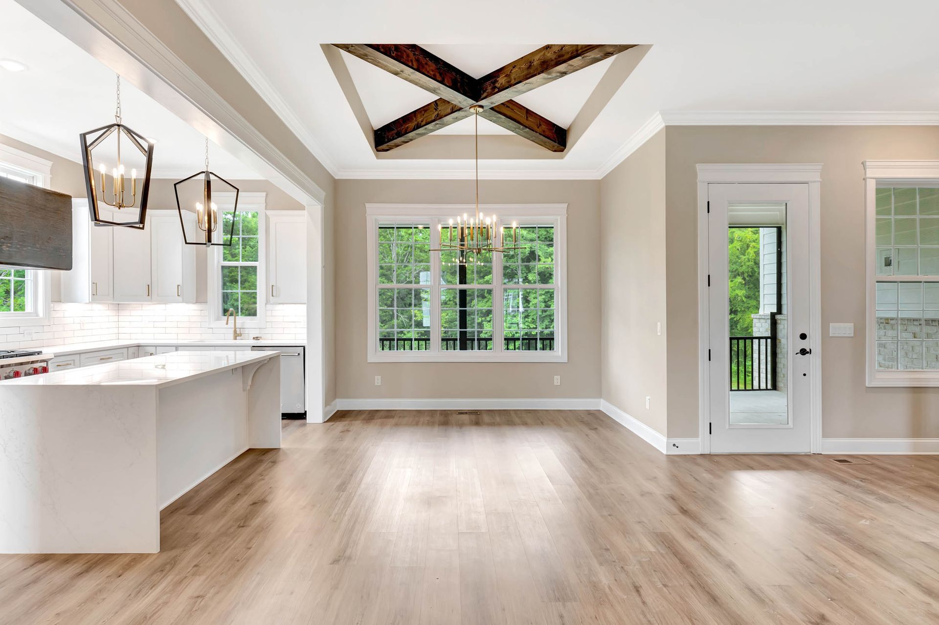 A large empty room with hardwood floors and a chandelier hanging from the ceiling.