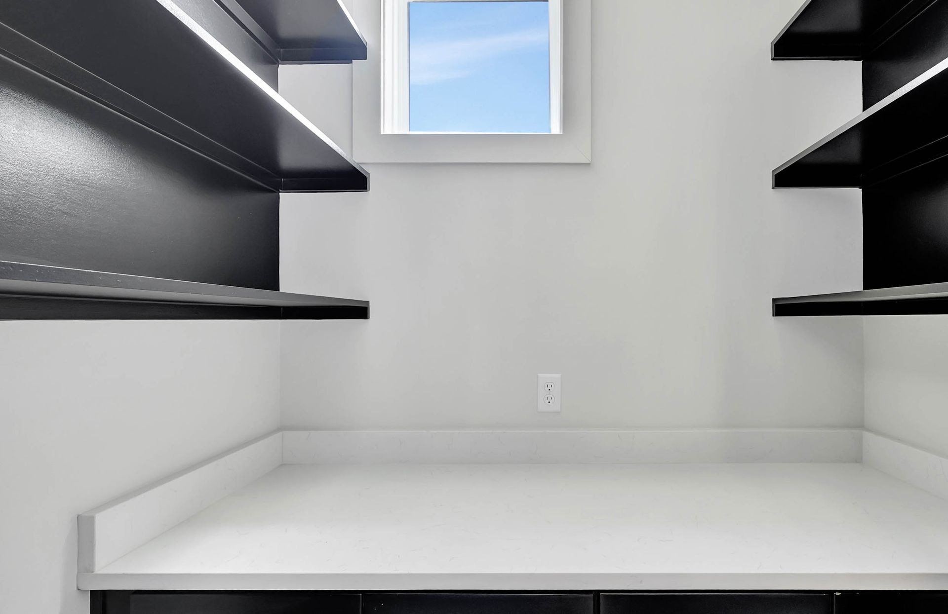 An empty room with black shelves and a window.