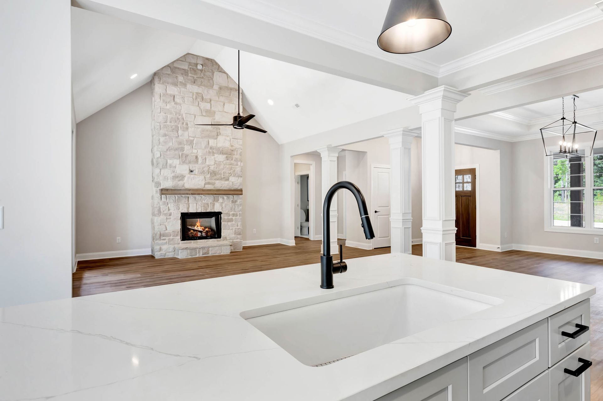 A kitchen with a sink and a fireplace in the background.