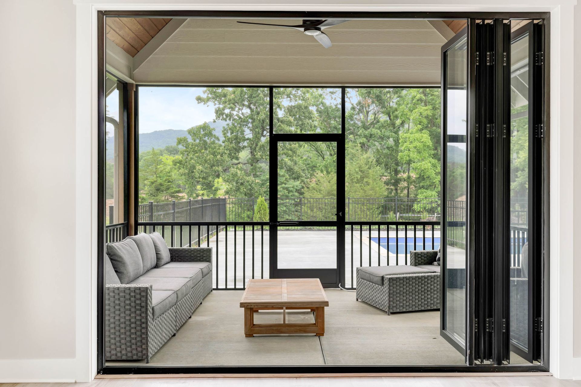 A screened in porch with a couch , table and chairs.