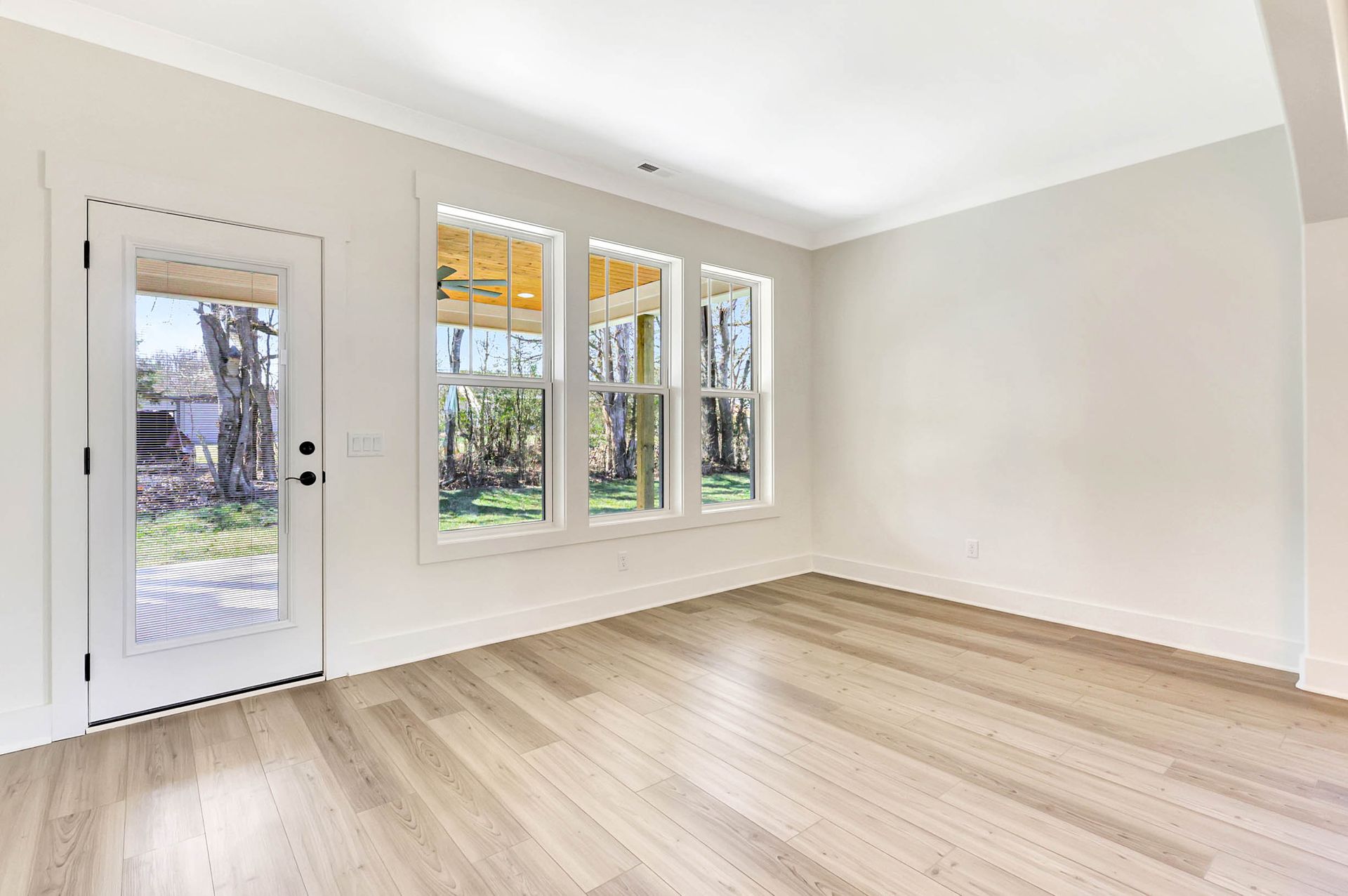 An empty living room with hardwood floors and white walls.