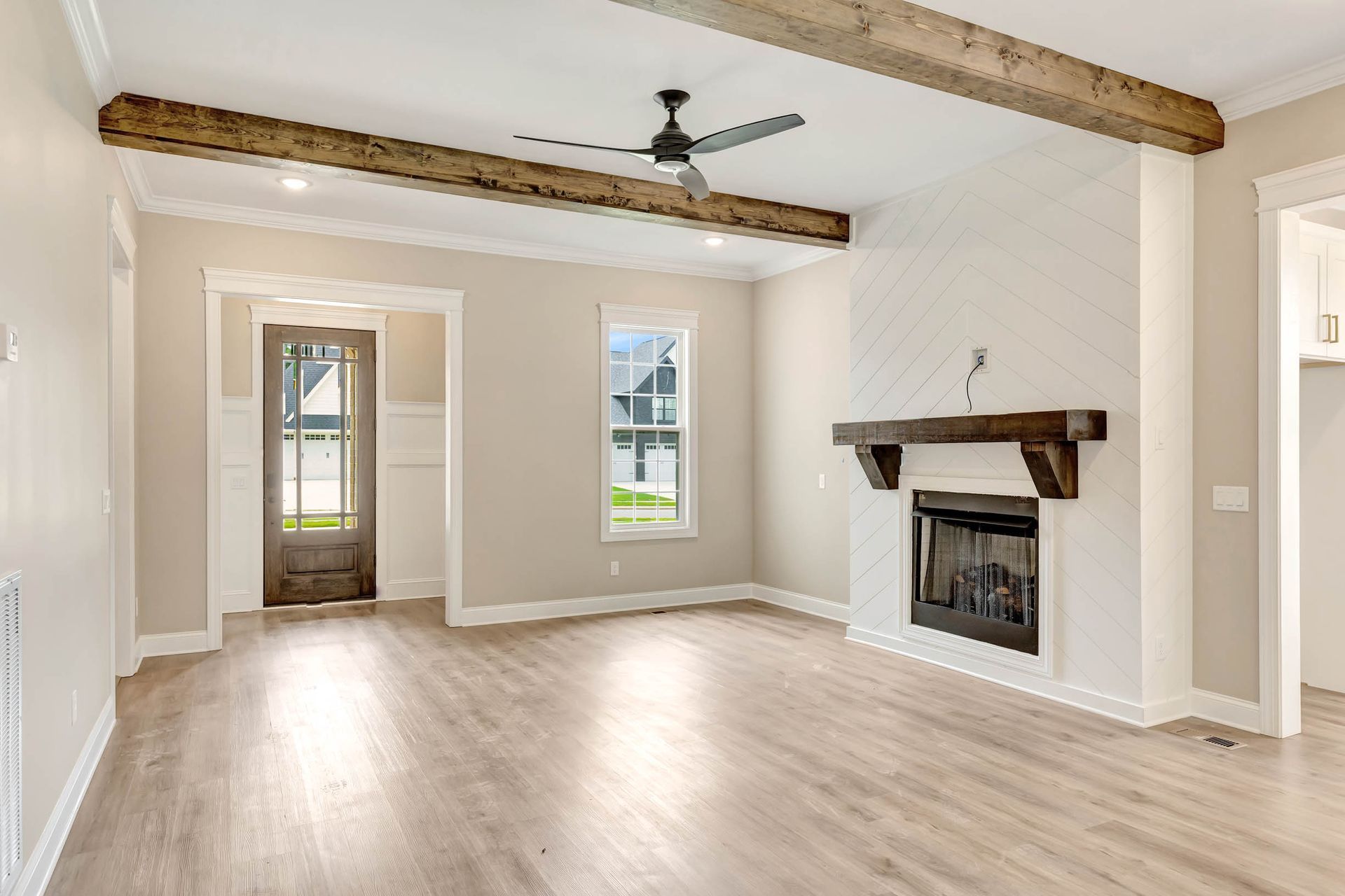 An empty living room with a fireplace and ceiling fan.
