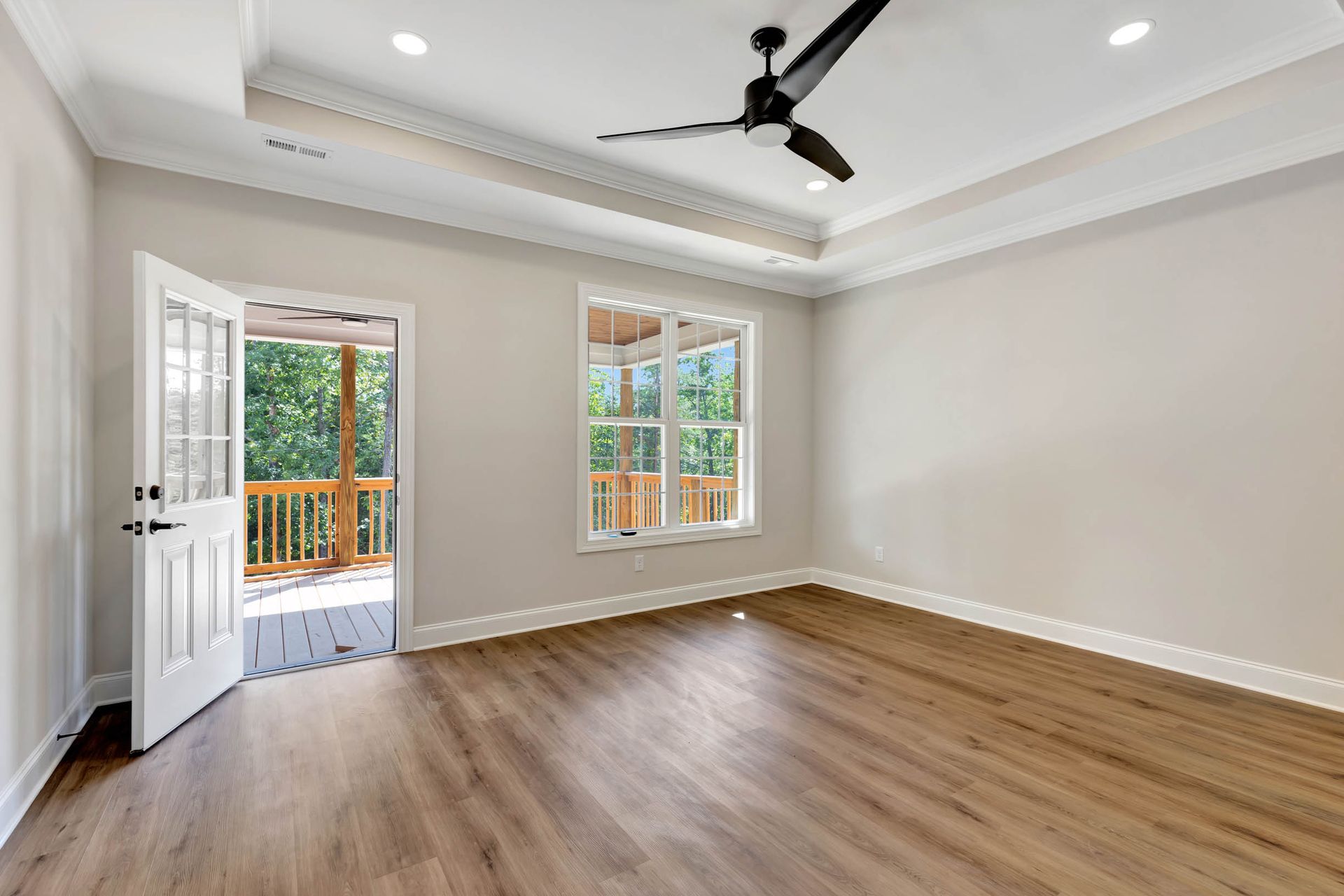 An empty room with hardwood floors and a ceiling fan.