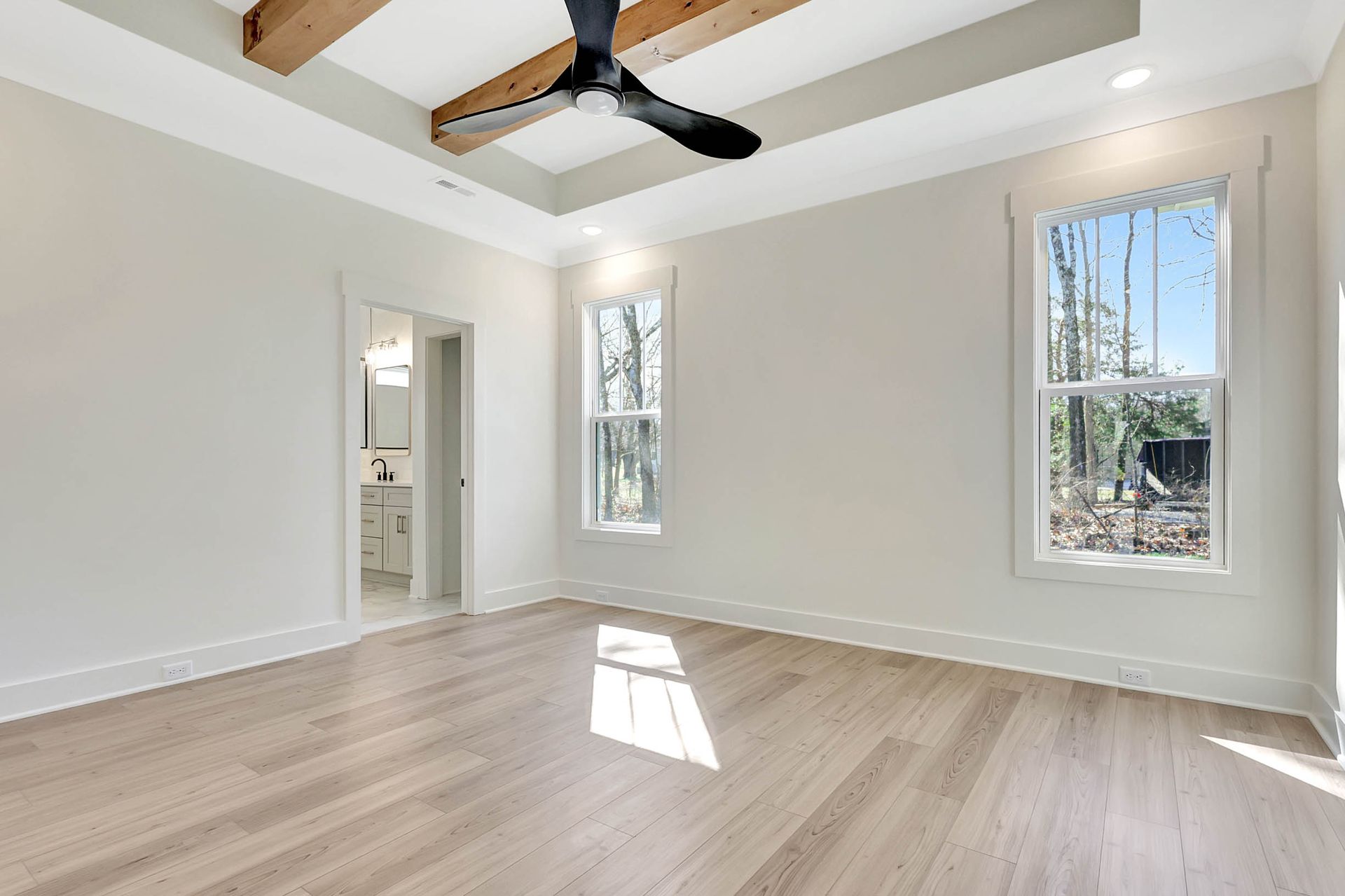 An empty room with hardwood floors and a ceiling fan.