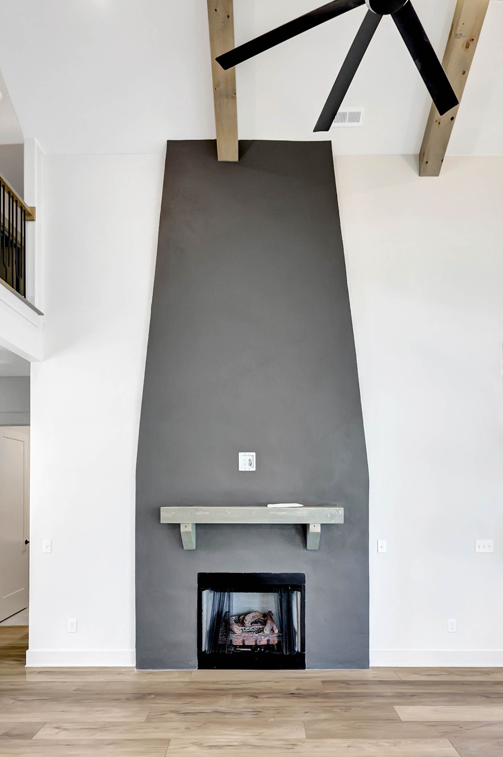 A living room with a fireplace and a ceiling fan.